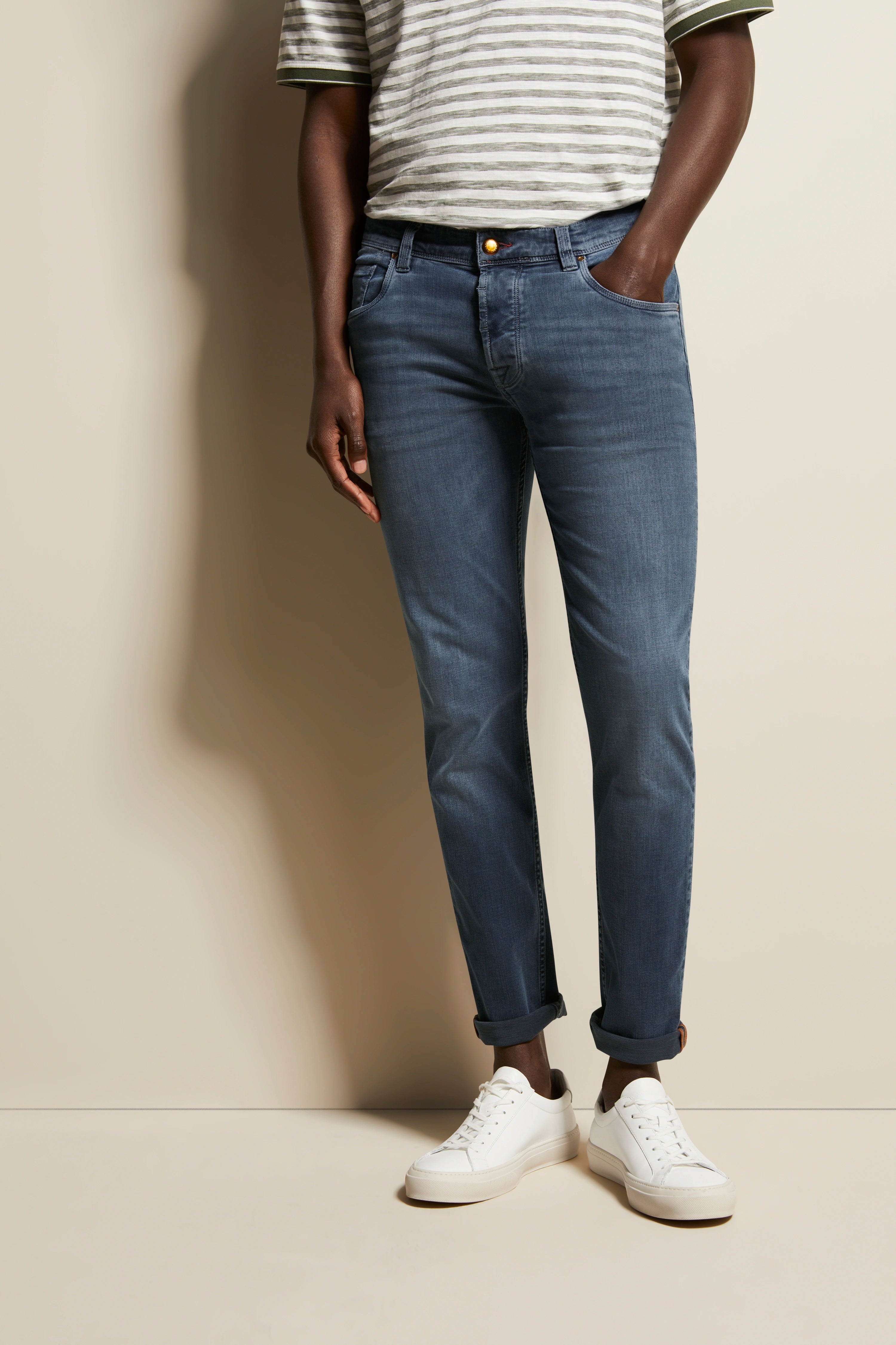 Gray striped T-shirt, blue jeans, white sneakers, casual model shot, hands in pockets.