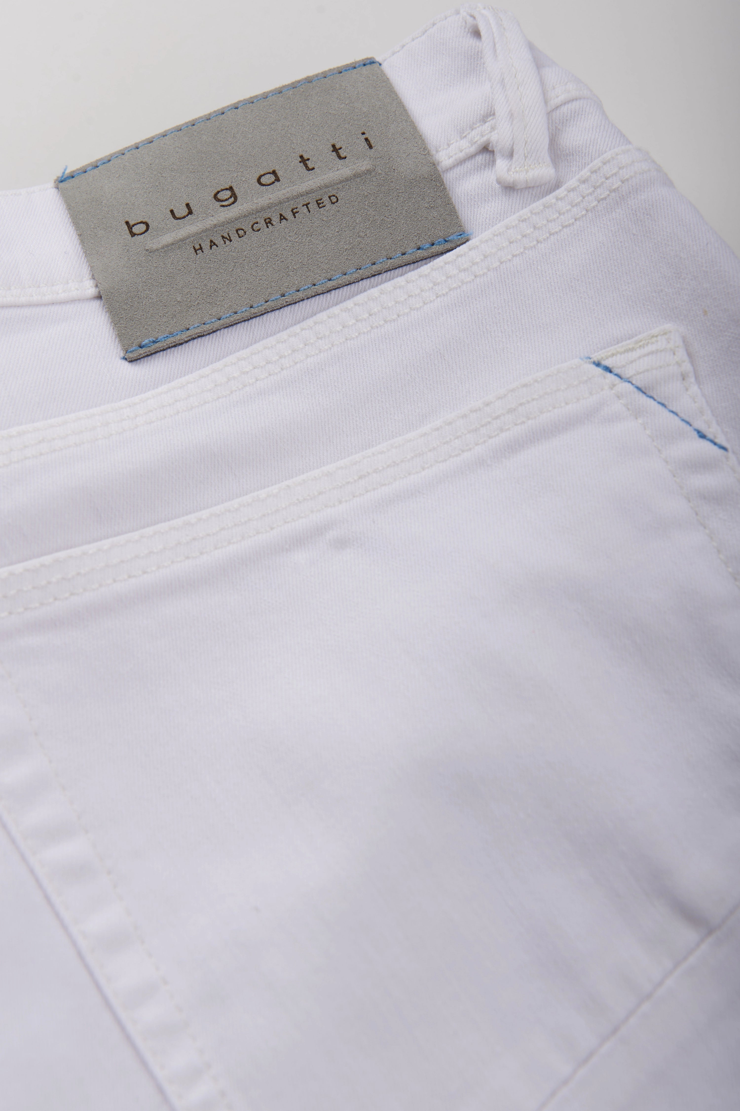 Weiße bugatti Jeans mit Label, Detailaufnahme, hochwertige Verarbeitung.