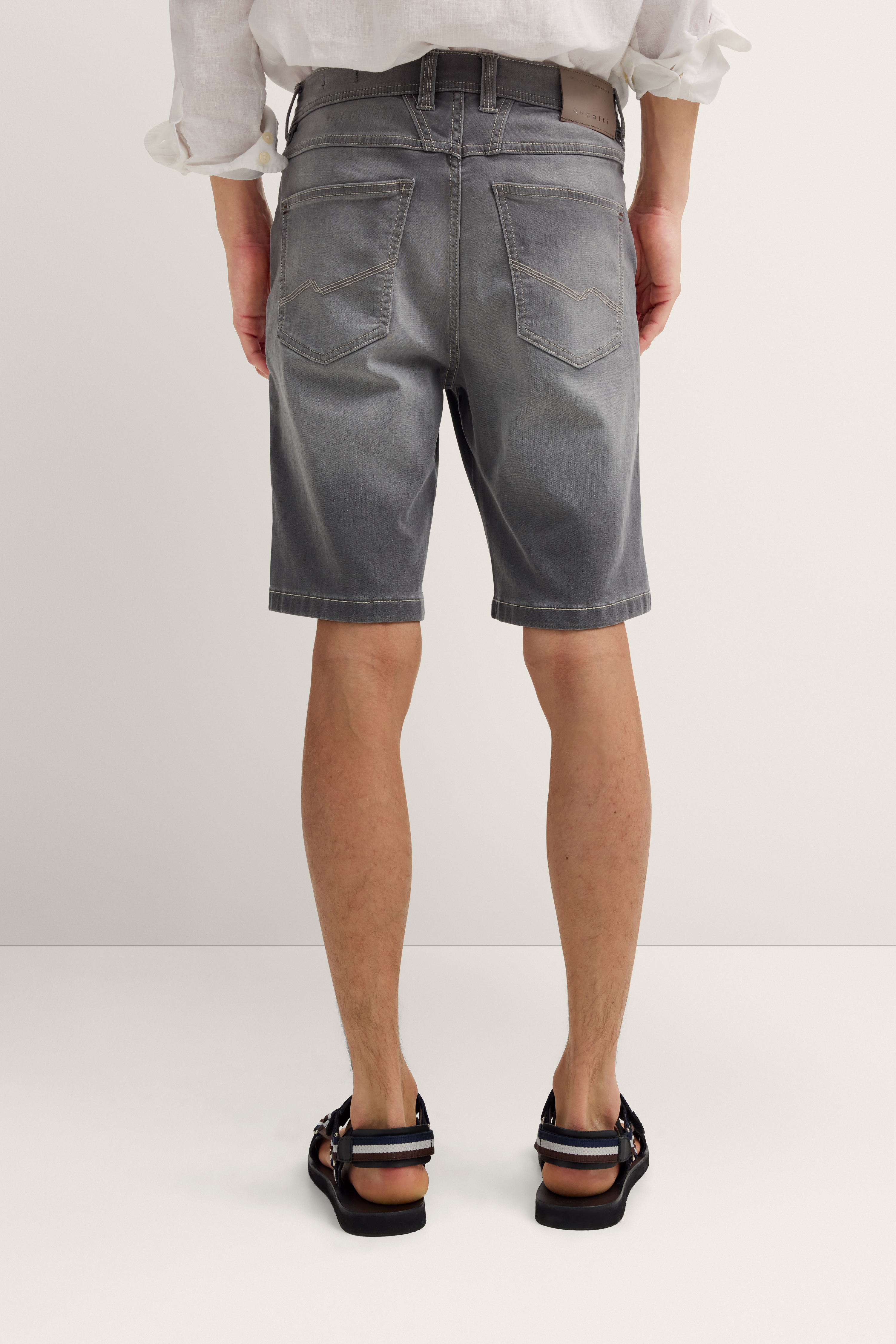 Graue Jeansshorts von bugatti, leger getragen, Rückansicht, kombiniert mit weißen Hemdärmeln.