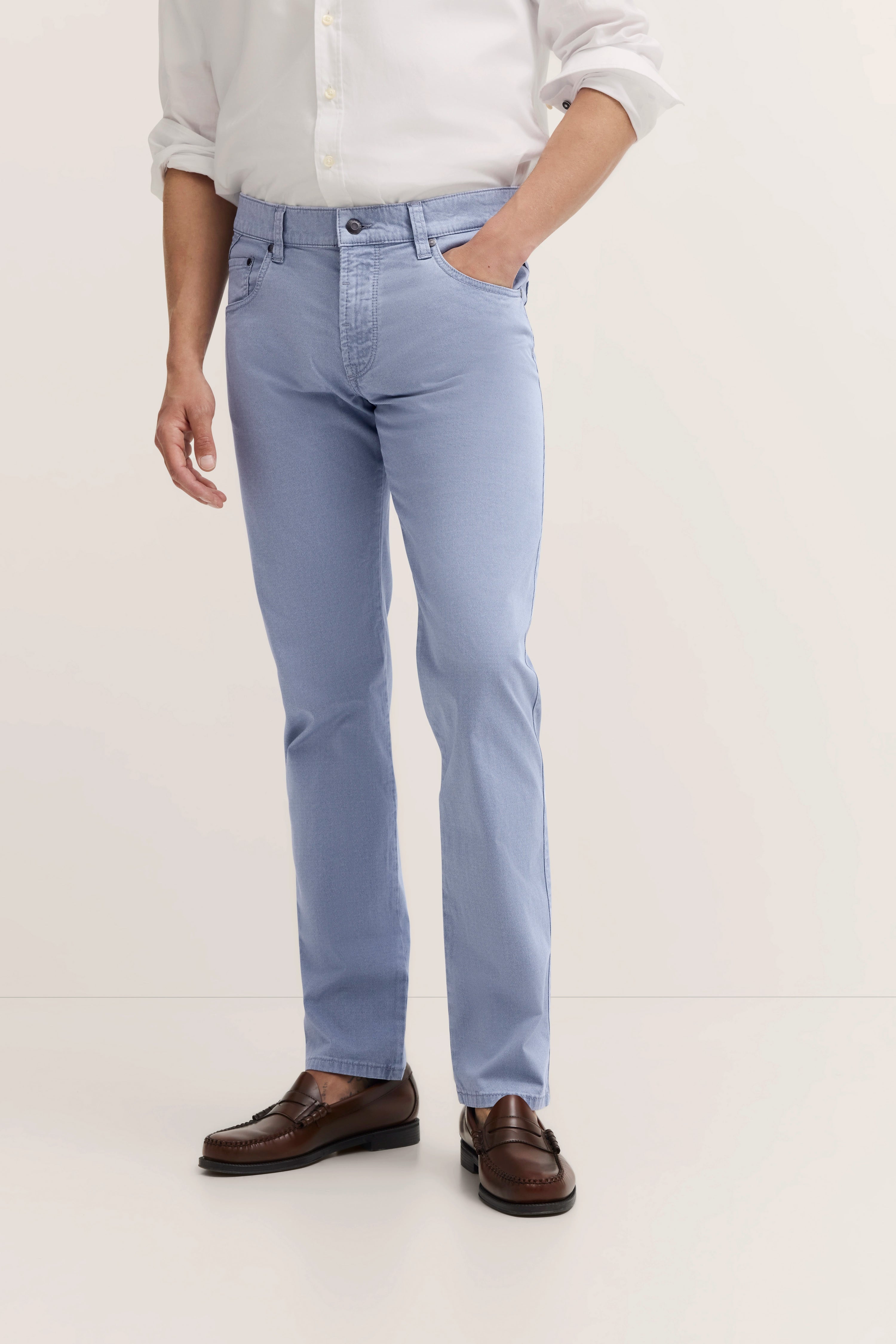 bugatti modelbeeld: Wit overhemd, lichtblauwe broek, bruine loafers, ontspannen pose, stijlvol en tijdloos.