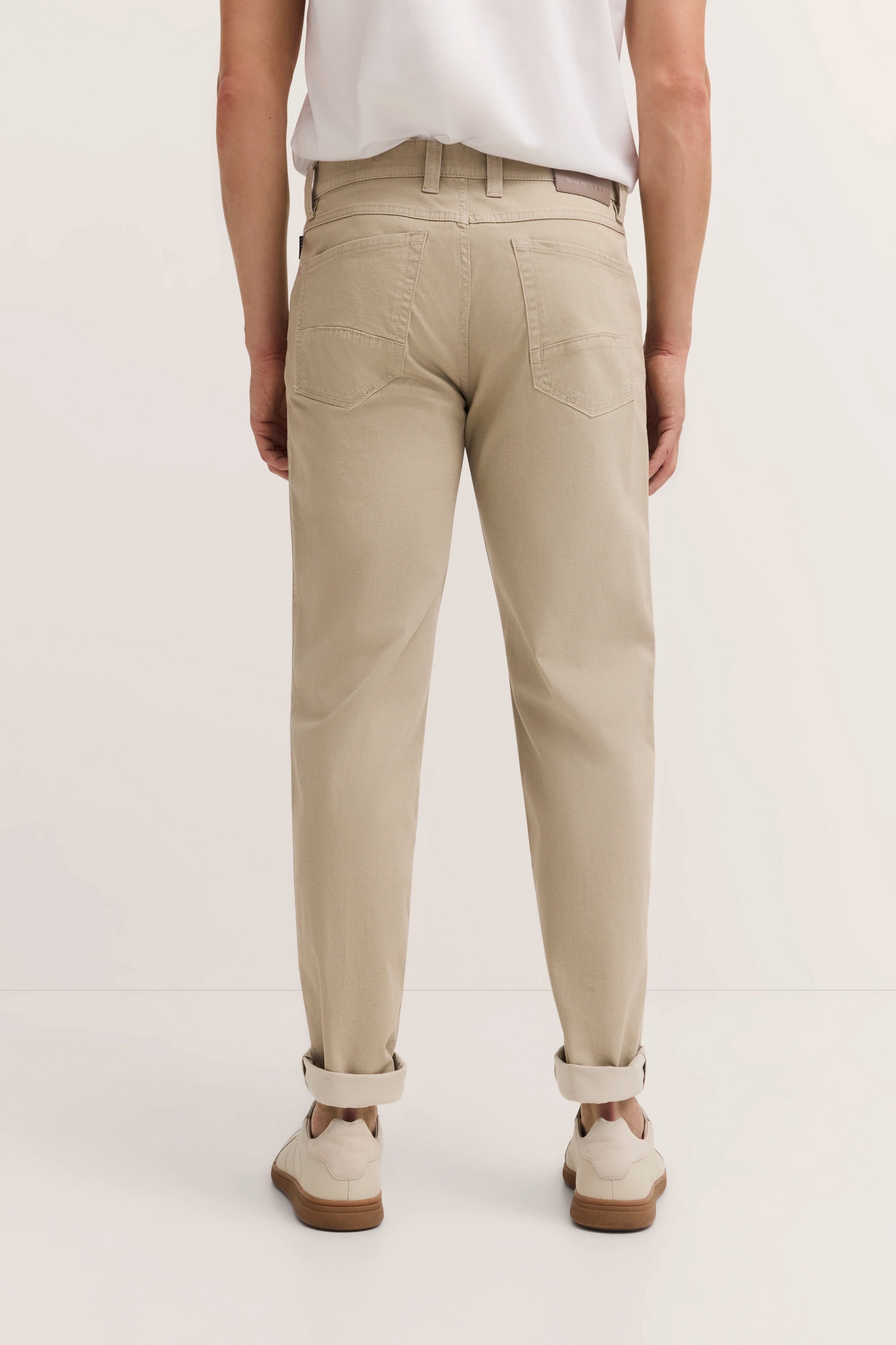 Beige Chino-Hose von bugatti, legeres Modelbild von hinten, mit weißem Shirt und beigen Schuhen.