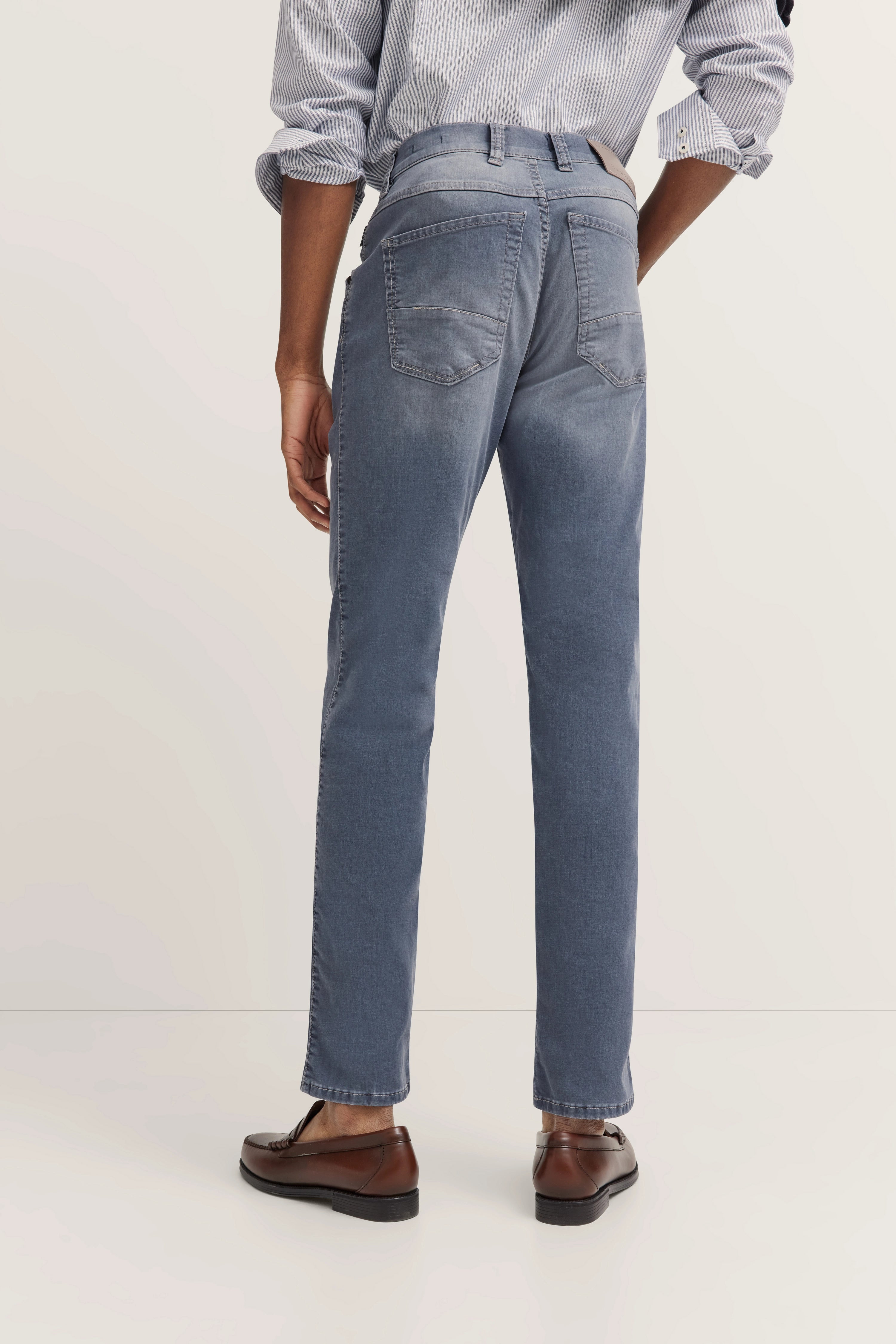 Rückansicht eines Models in blauen bugatti Jeans und braunen Schuhen, legerer Look.