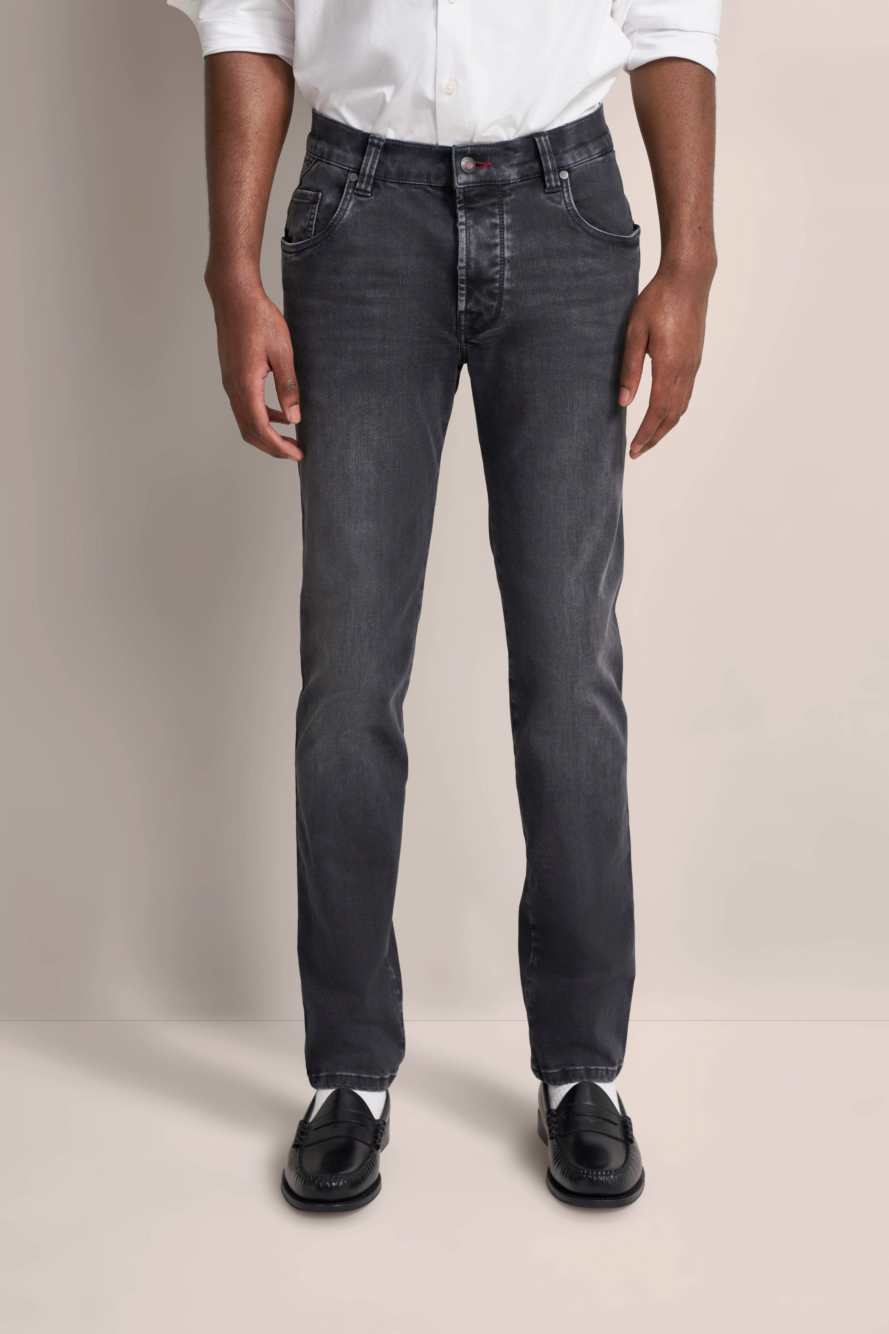 bugatti Modelbild: Mann in schwarzer Jeans, weißem Hemd. Klassisch, entspannte Pose.