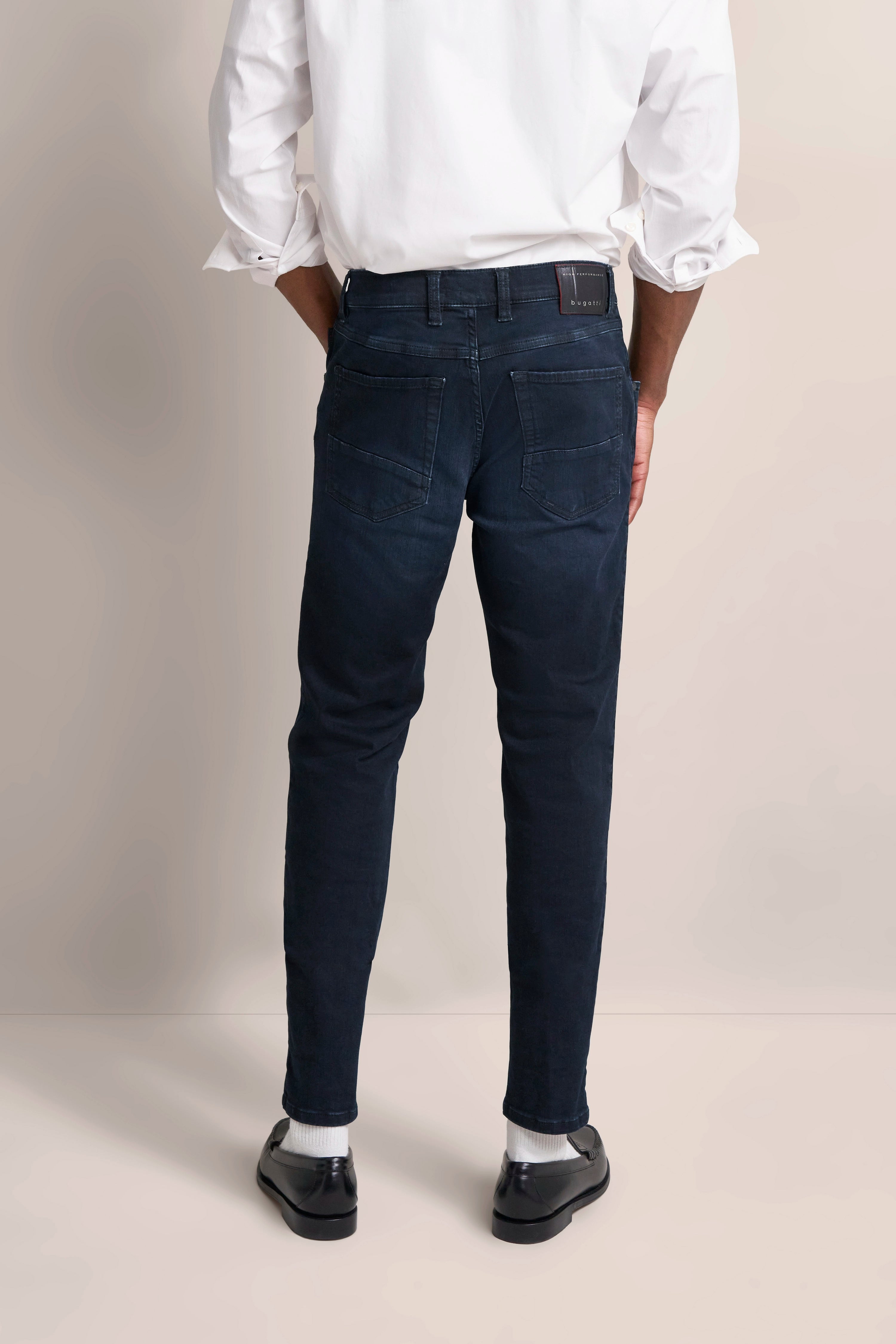 Weiße Hemd, dunkelblaue Jeans von bugatti, Modelbild von hinten, lässige Pose.