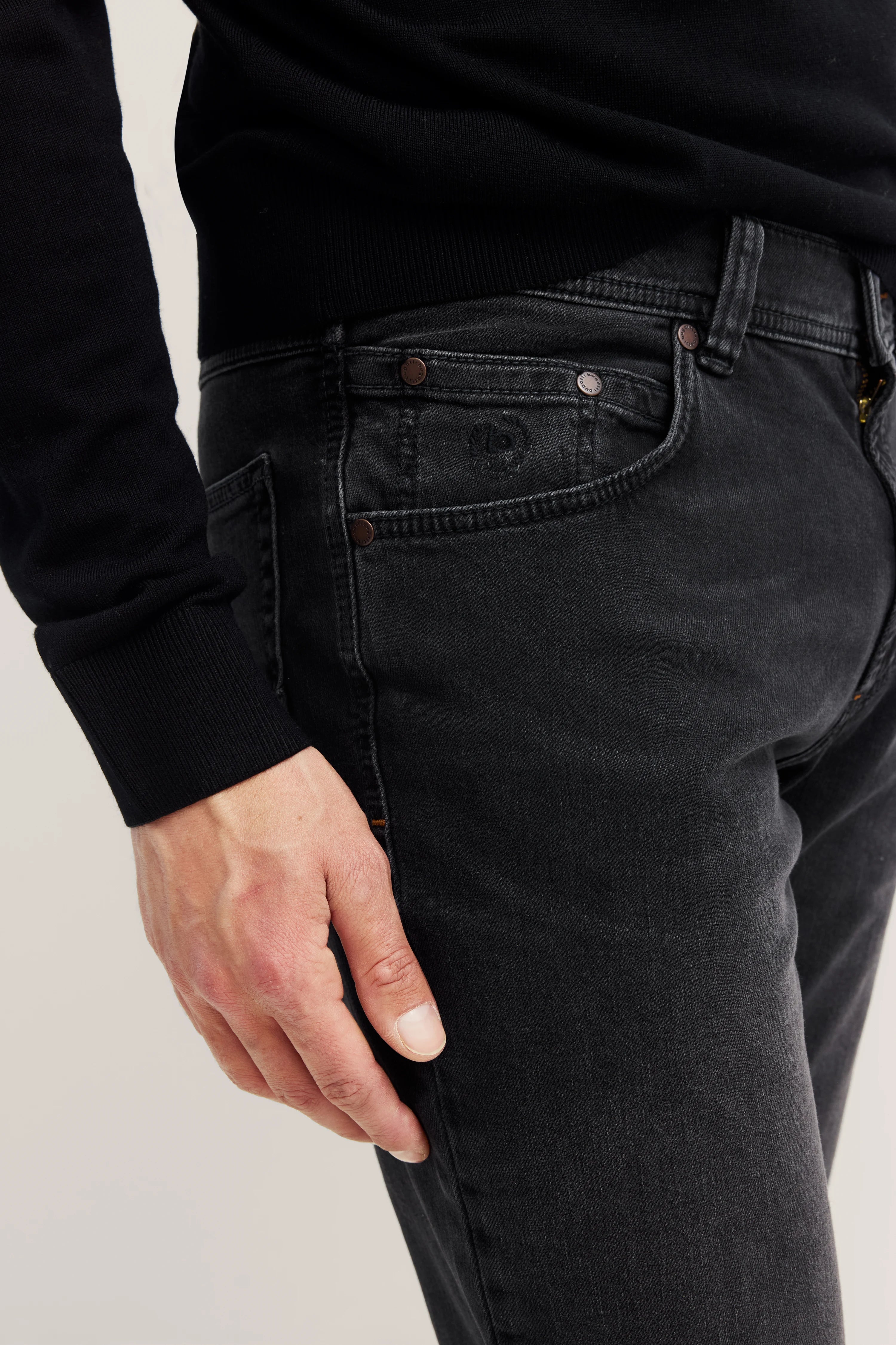 Schwarze bugatti Jeans, Detailansicht, legeres Bild, schwarze Jacke sichtbar.