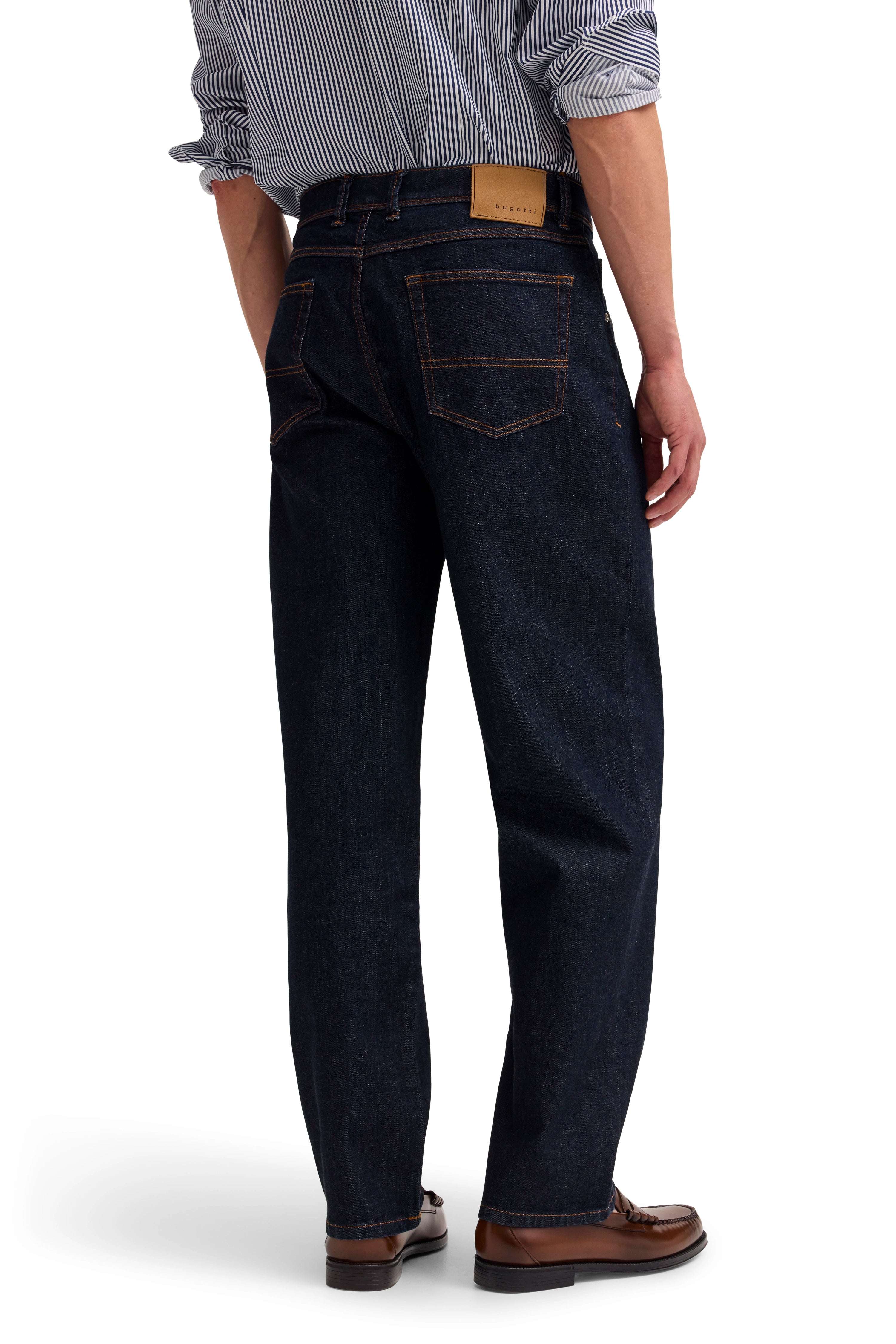 Dunkelblaue Jeans von bugatti, gestreiftes Hemd, braune Schuhe, Model rückseitig stehend.