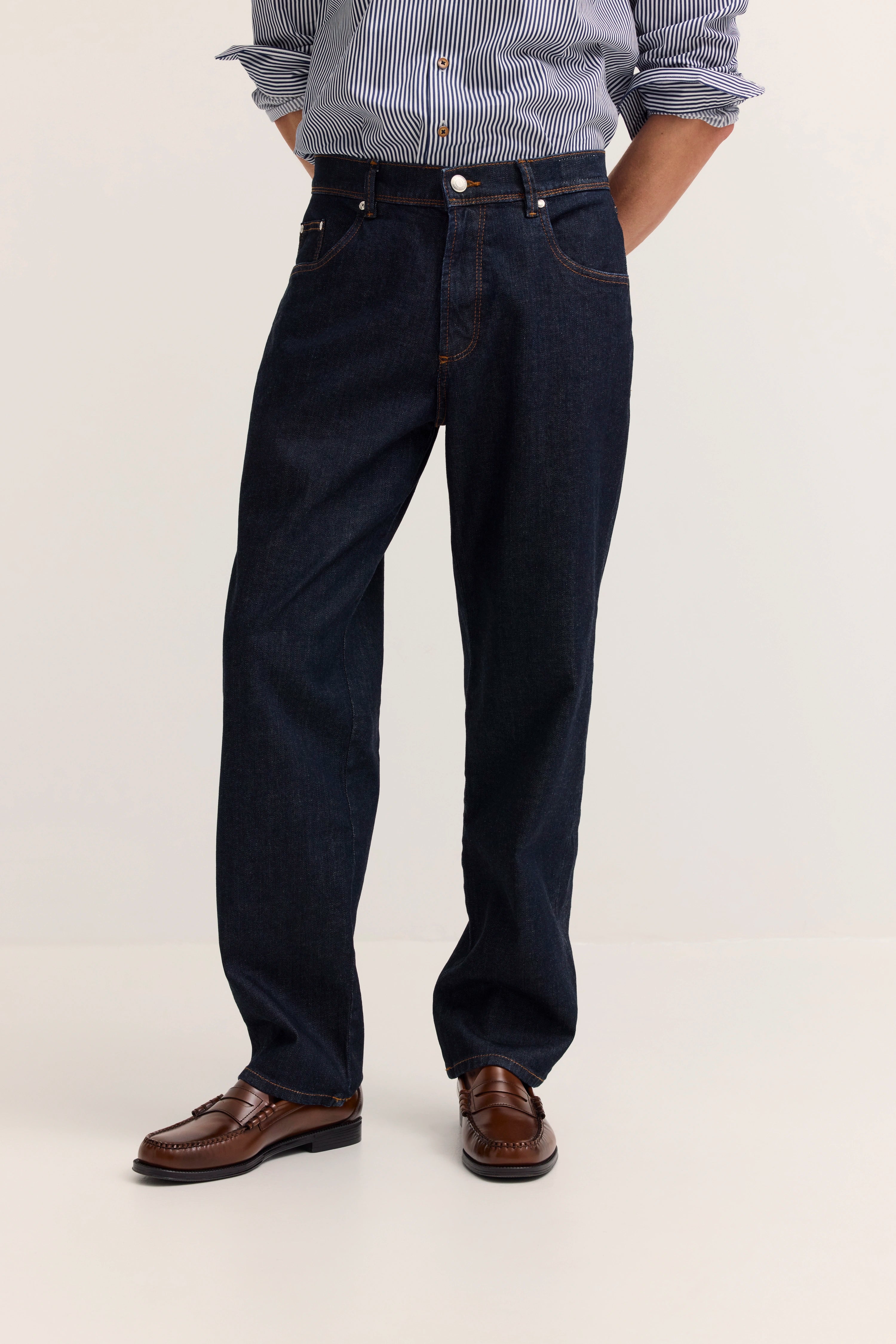 Blau-weiß gestreiftes Hemd, dunkelblaue Jeans, braune Loafer, legeres Modelbild.