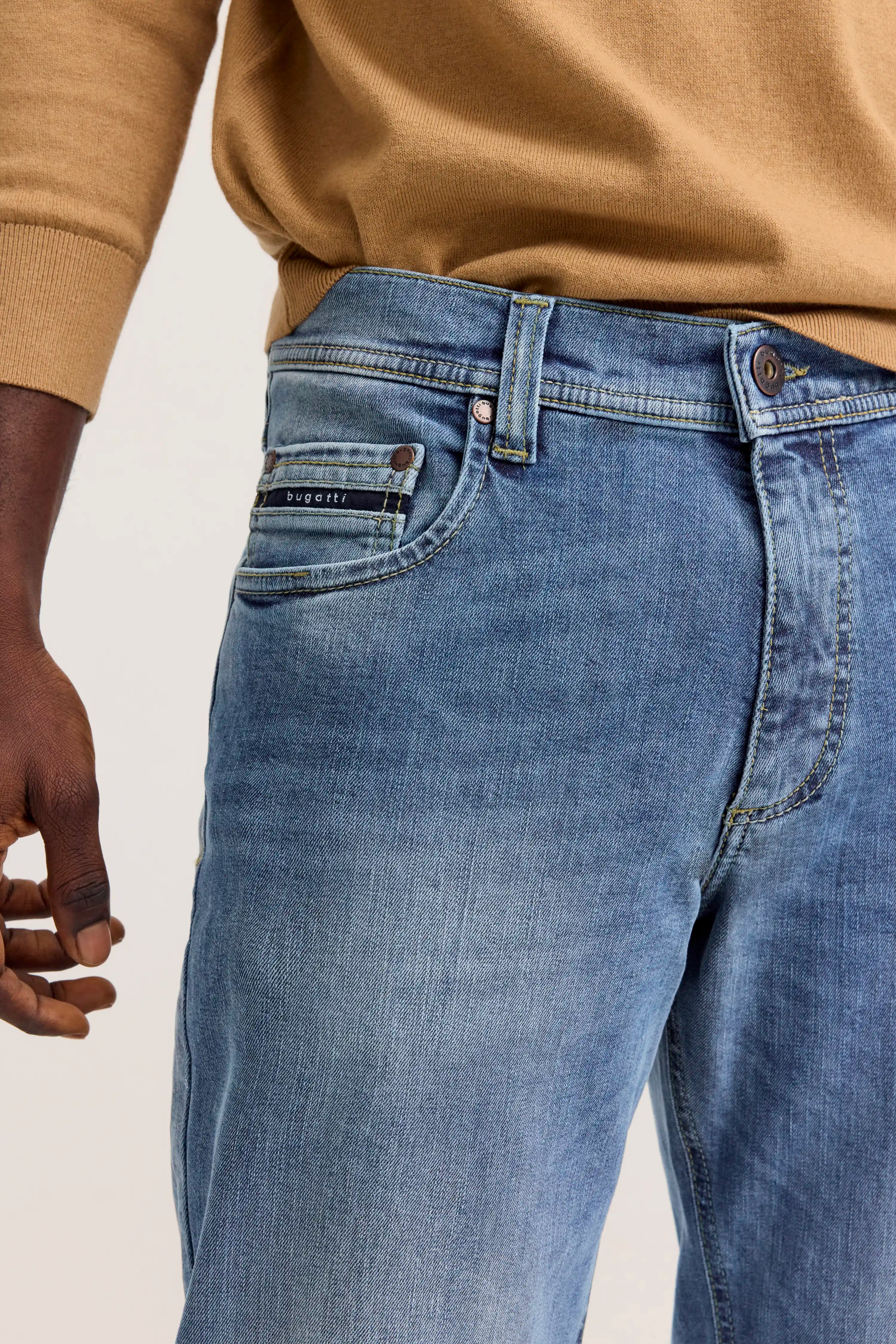 Jeans in Blau, legeres Modelbild von hinten, schwarzer Schuh, weißes T-Shirt.