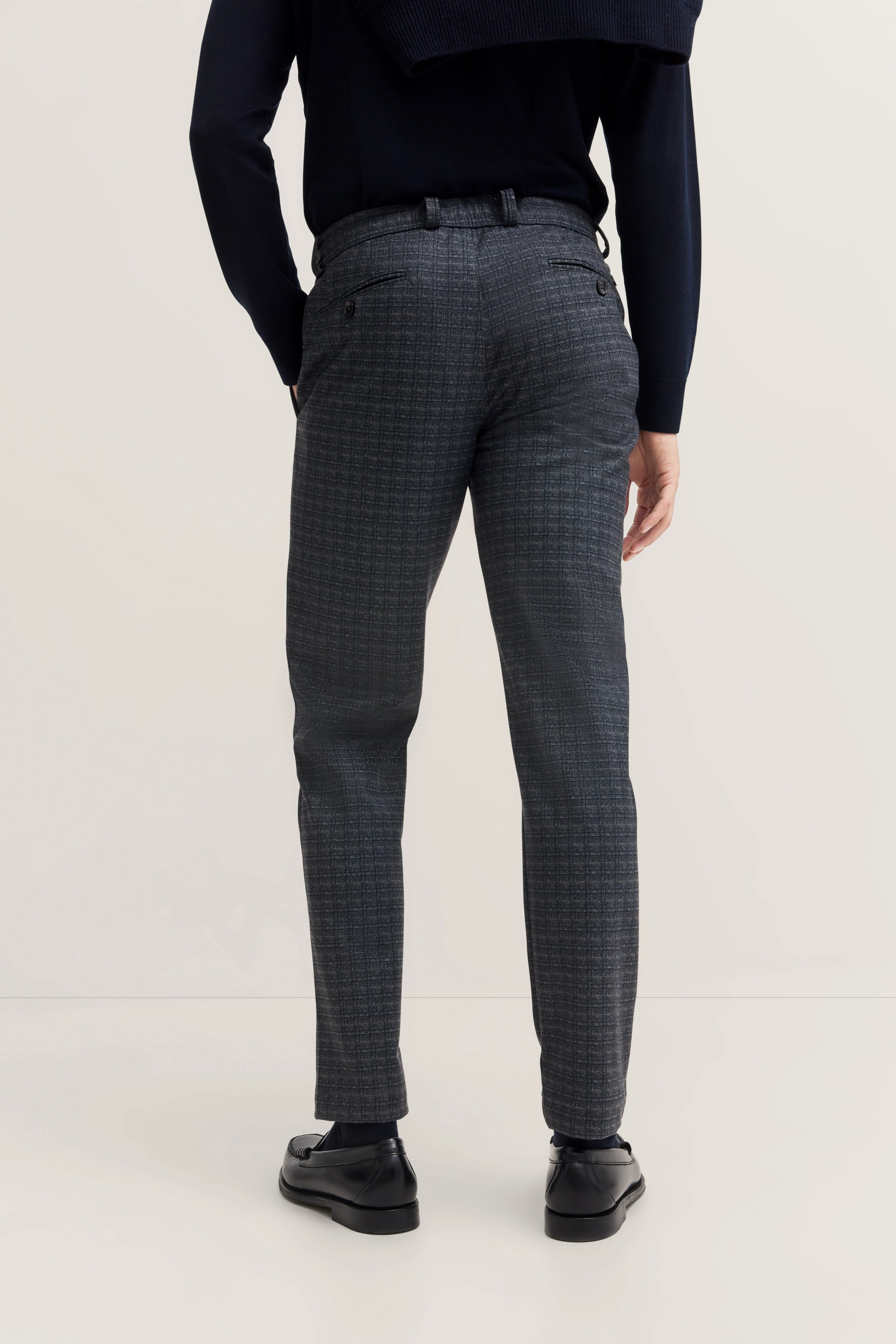 bugatti model in navy jacket, gray checkered pants, back view, casual pose.