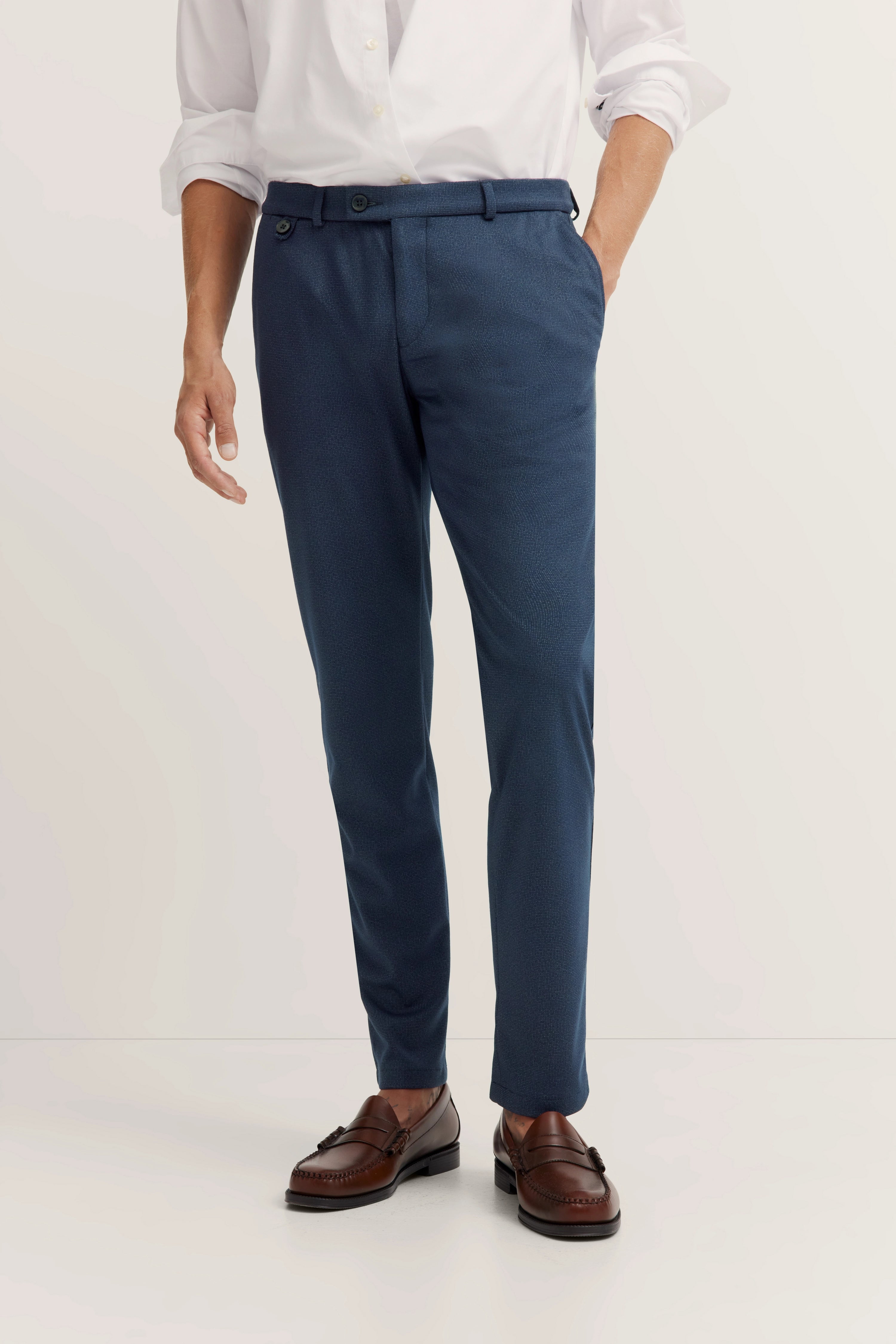 Weiße Hemd und blaue Hose von bugatti, legerer Stil, braune Loafer, Model im Stehen.