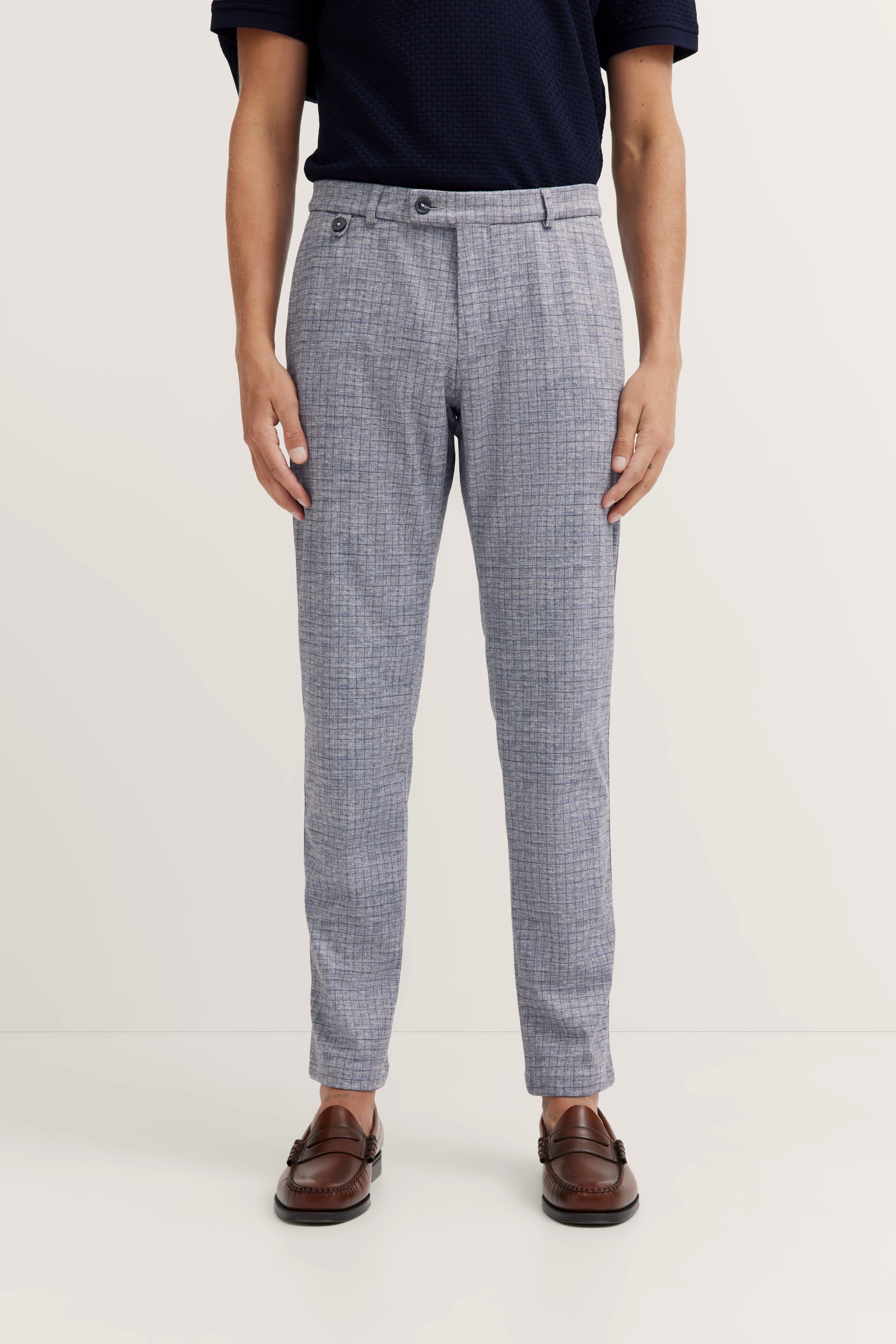 Grijze geruite bugatti broek, casual stijl, model in ontspannen houding, donkerblauw shirt, bruine schoenen.
