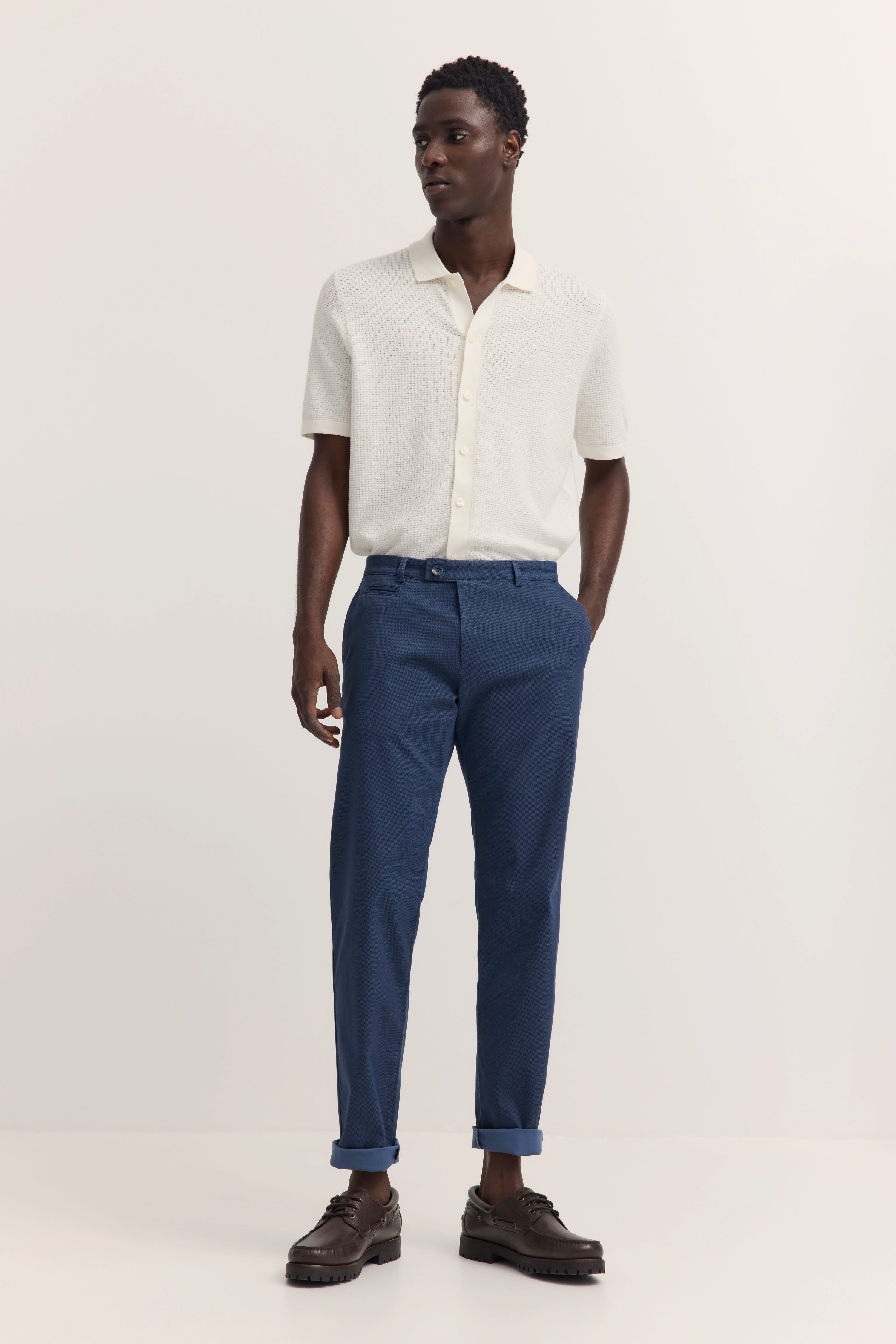 Weiße Strick-Polo mit blauer Chino, legeres Modelbild, entspannte Haltung.
