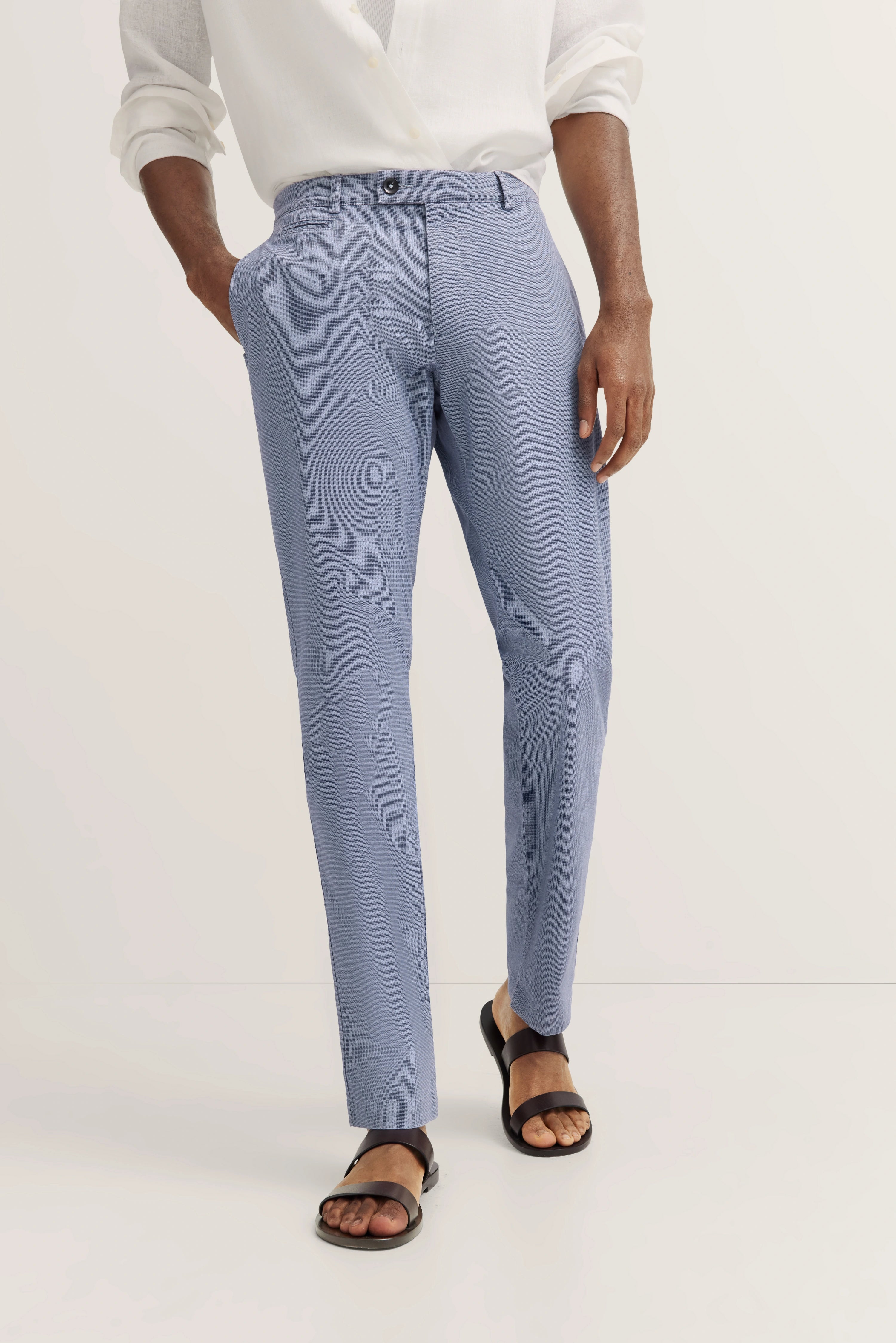 Hellblauer Anzughose von bugatti, legeres Modelbild, weiße Bluse und braune Sandalen.