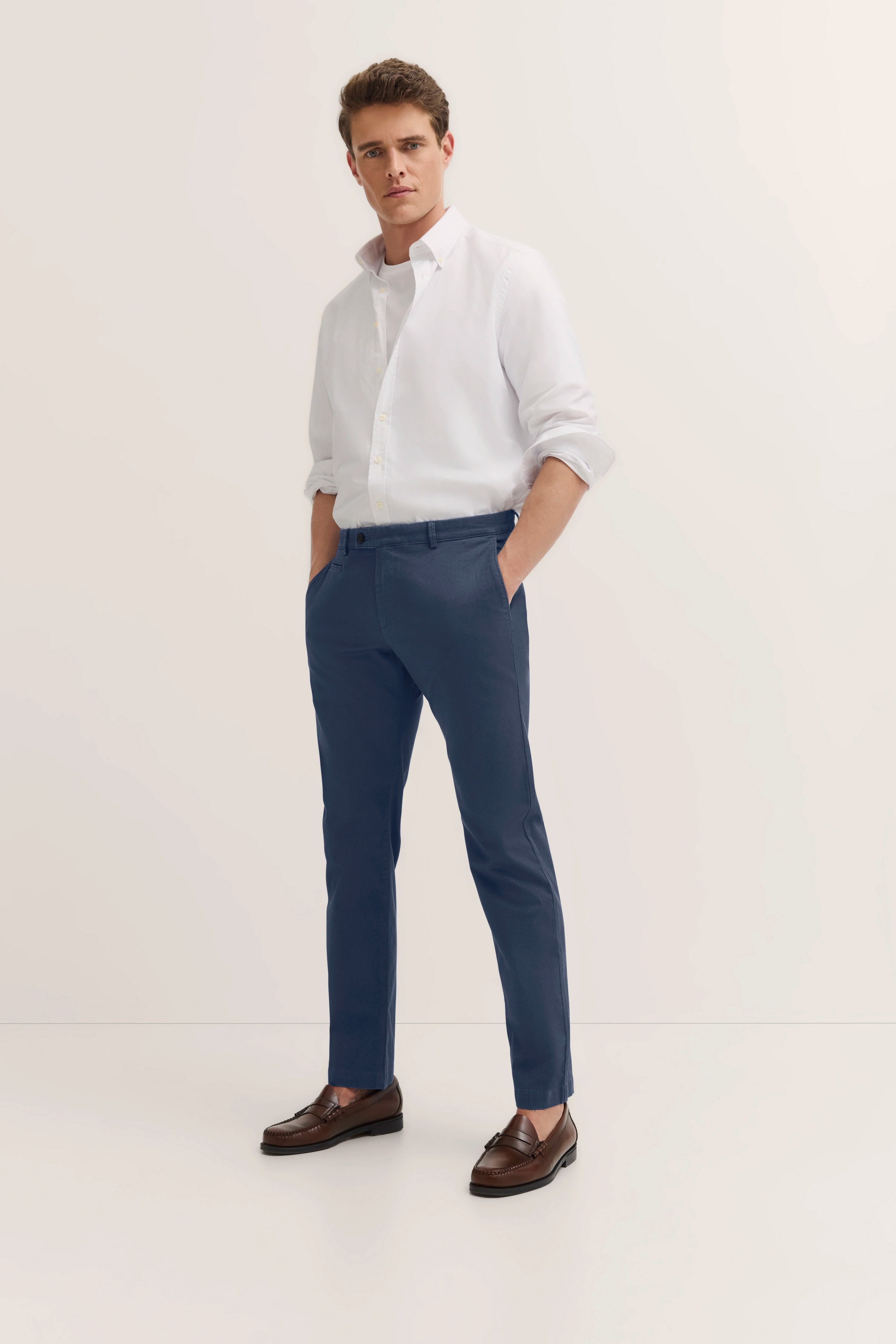Weißes Hemd, blaue Hose, braune Schuhe, Modelbild, lässige Pose, bugatti Stil.