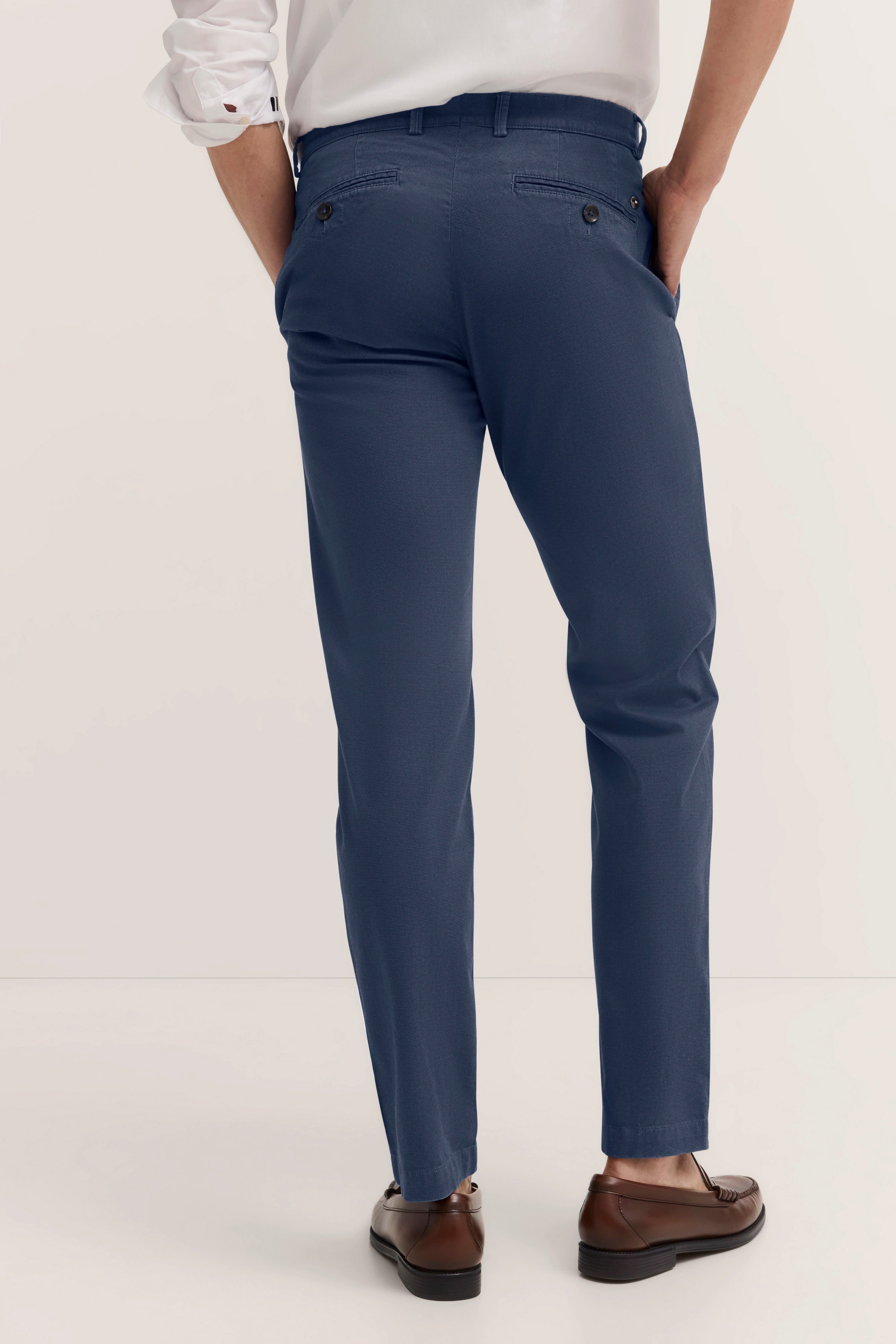 Blaues bugatti-Büro-Outfit: Chino-Hose, braune Schuhe, Model von hinten, Hände in Hosentaschen.