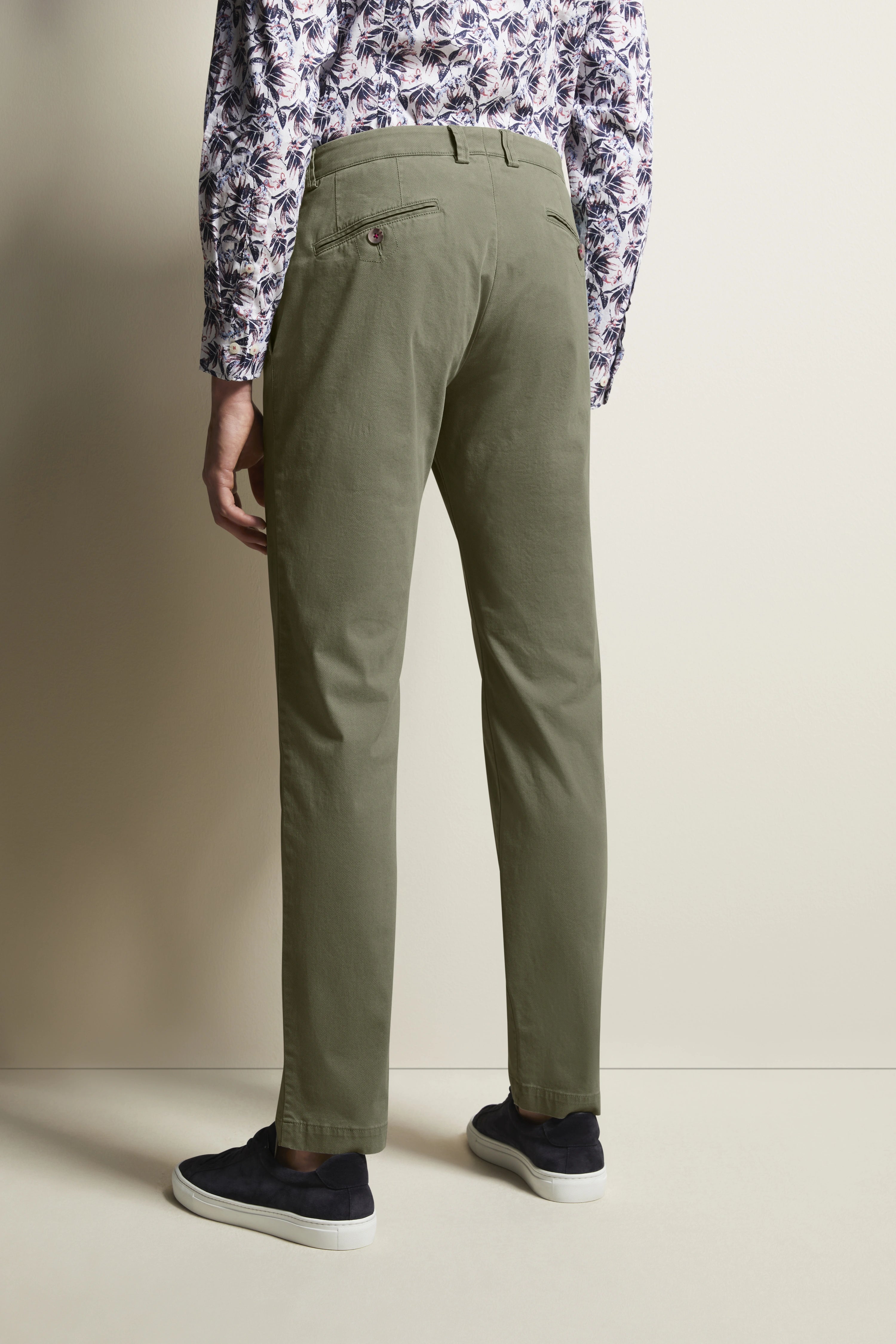 Grünes Chino-Outfit mit floralem Musterhemd, legeres Modelbild, Rückenansicht, entspannte Haltung.