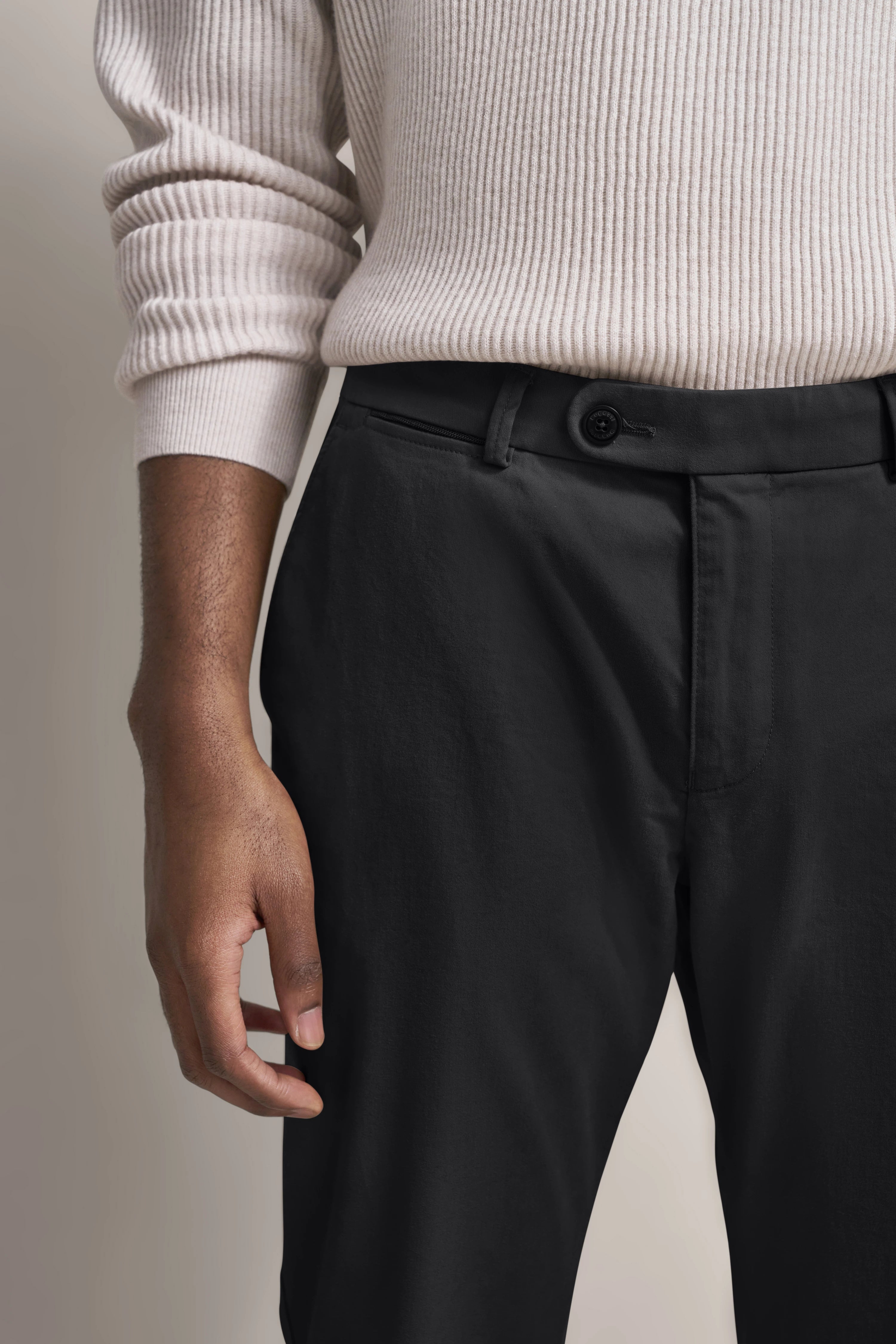 Büstenbild: Weißer Strickpullover, schwarze Hose, schlicht und elegant im Stil von bugatti.