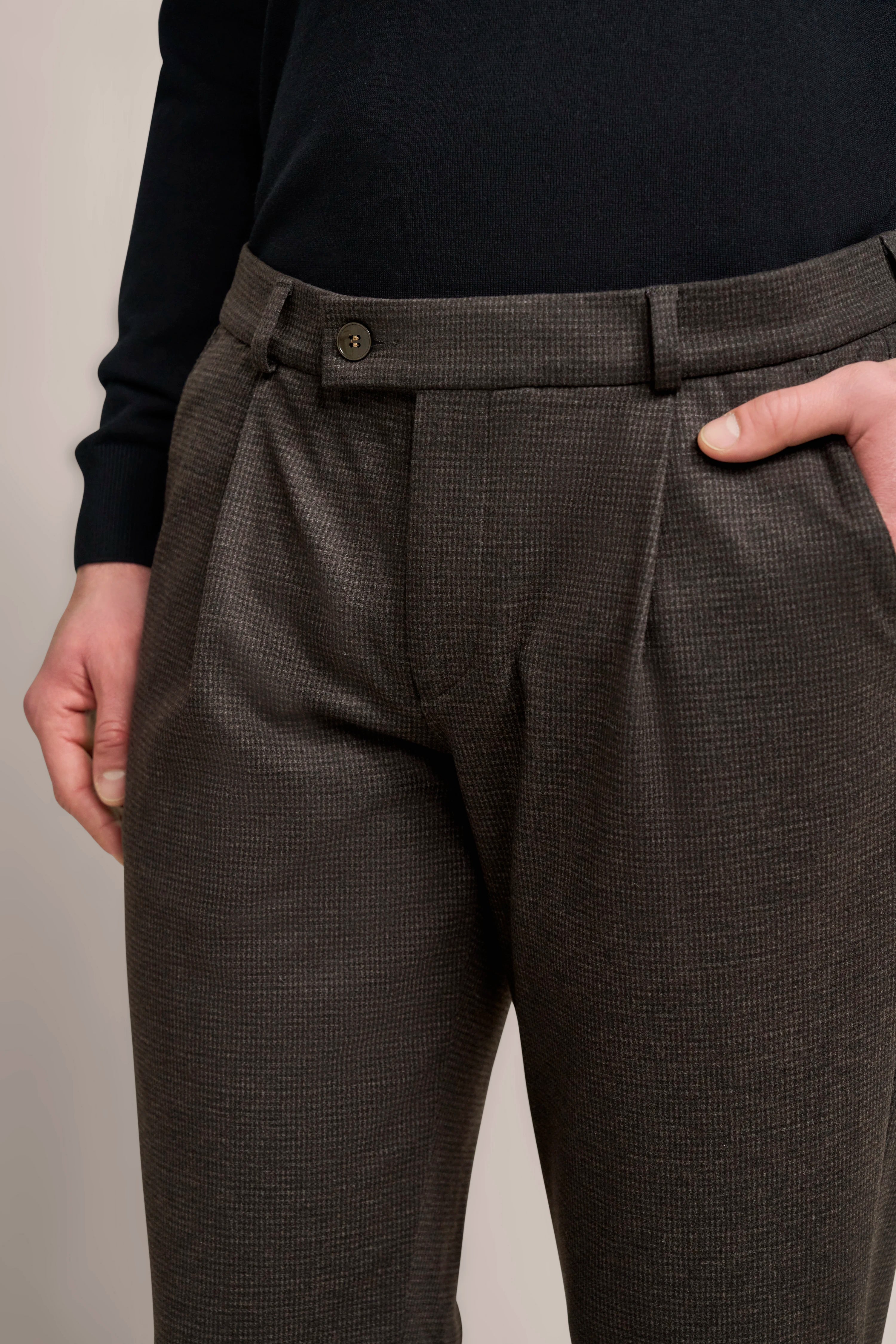 Hose in Braun mit feinem Muster, legeres Modelbild, Hand in Hosentasche.