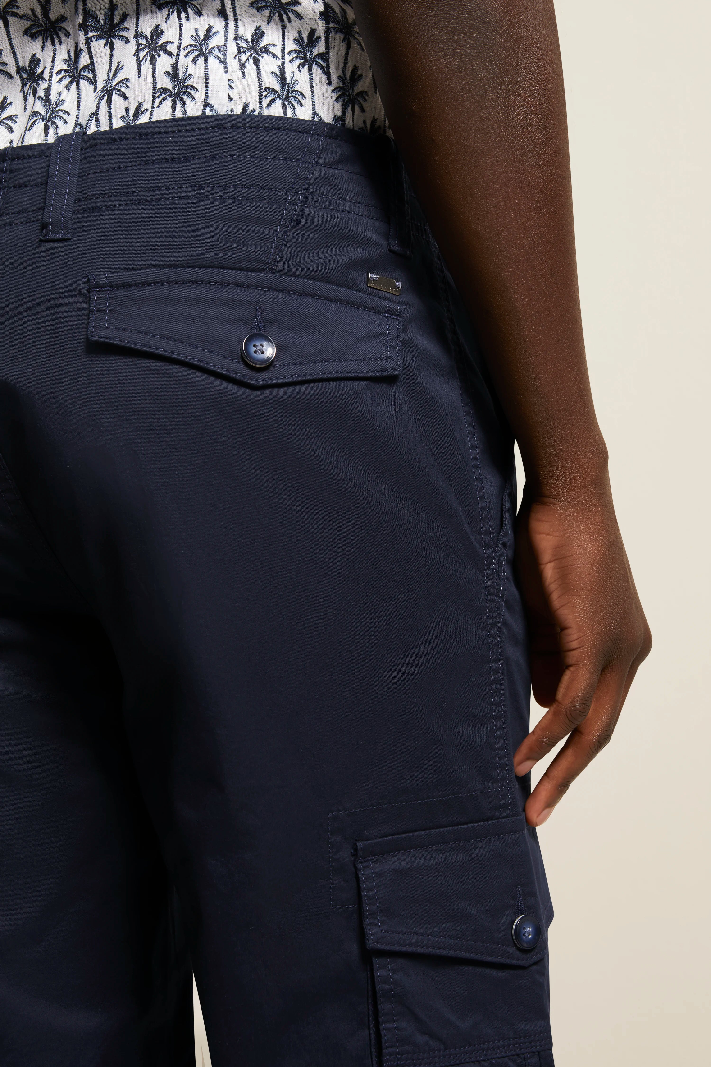 Navy-Shorts von bugatti mit Seitentaschen, legeres Büstenbild, Hemd mit Palmenmuster im Hintergrund.