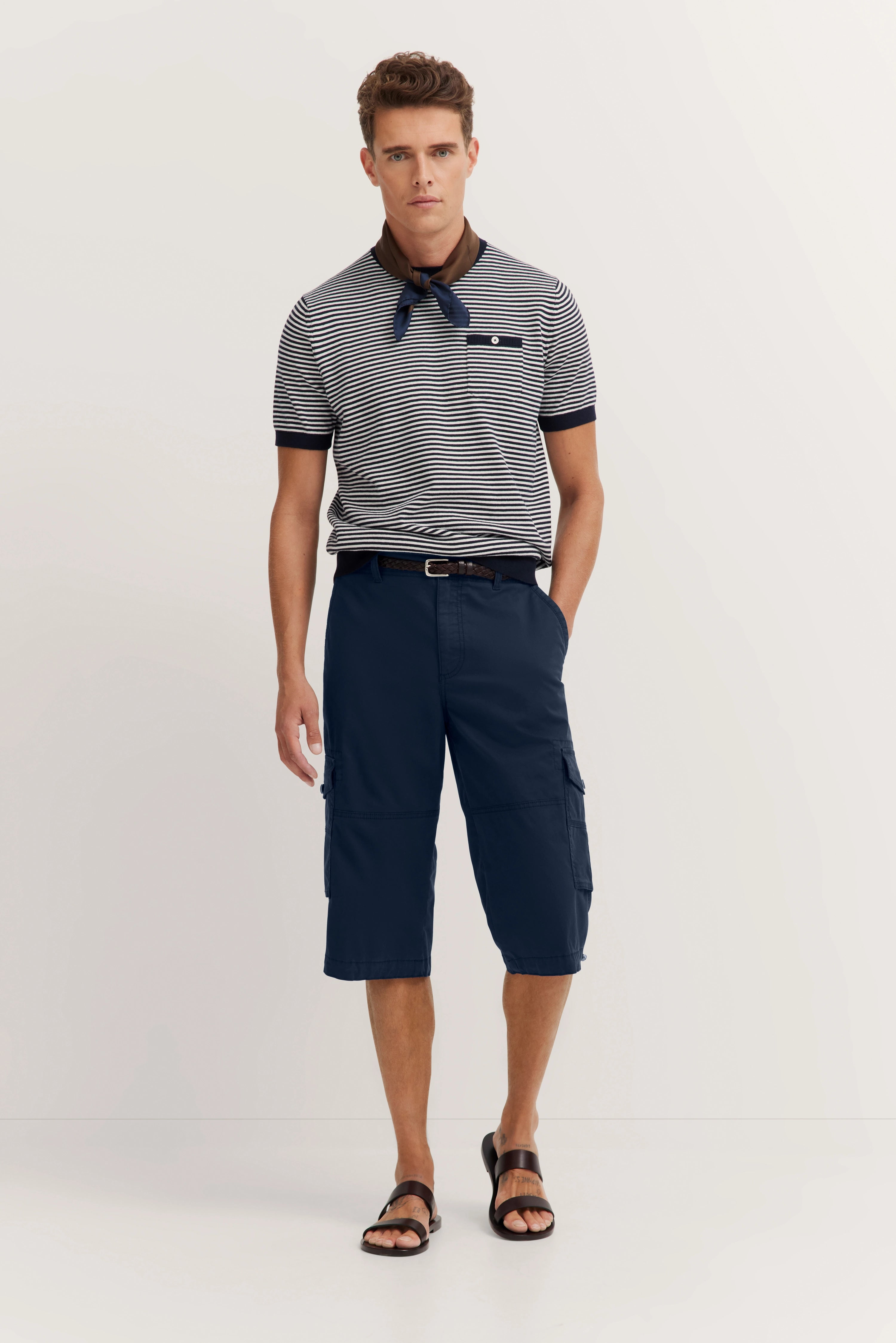 bugatti striped polo in navy, dark blue cargo shorts, model standing in relaxed pose, embodying Italian elegance.