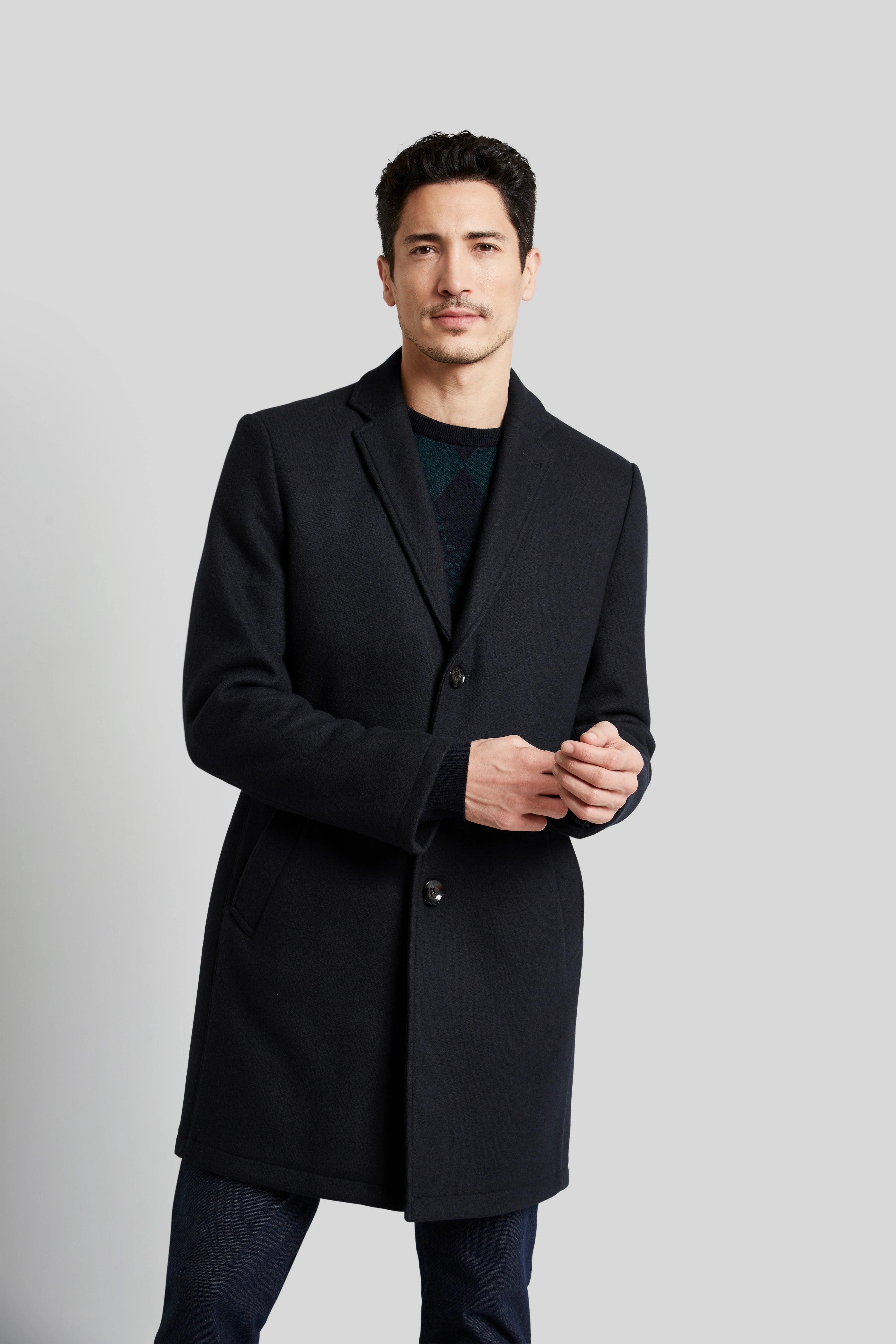 bugatti Mantel in Schwarz, Modelbild, legeres Posing, eleganter Look mit Pullover und Jeans