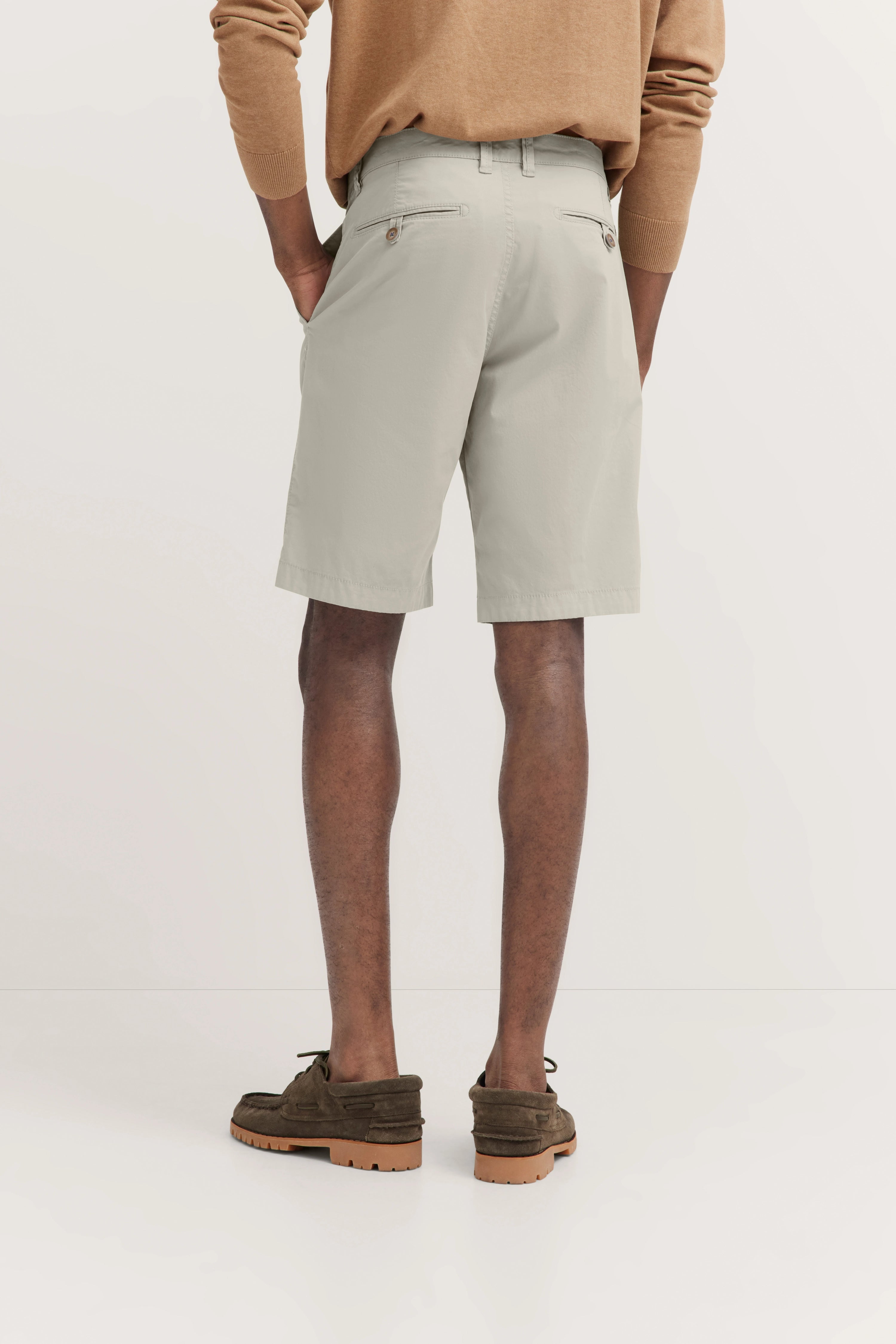 Herren-Model von hinten in beige Shorts, braunem Pullover und dunkelgrünen Schuhen.