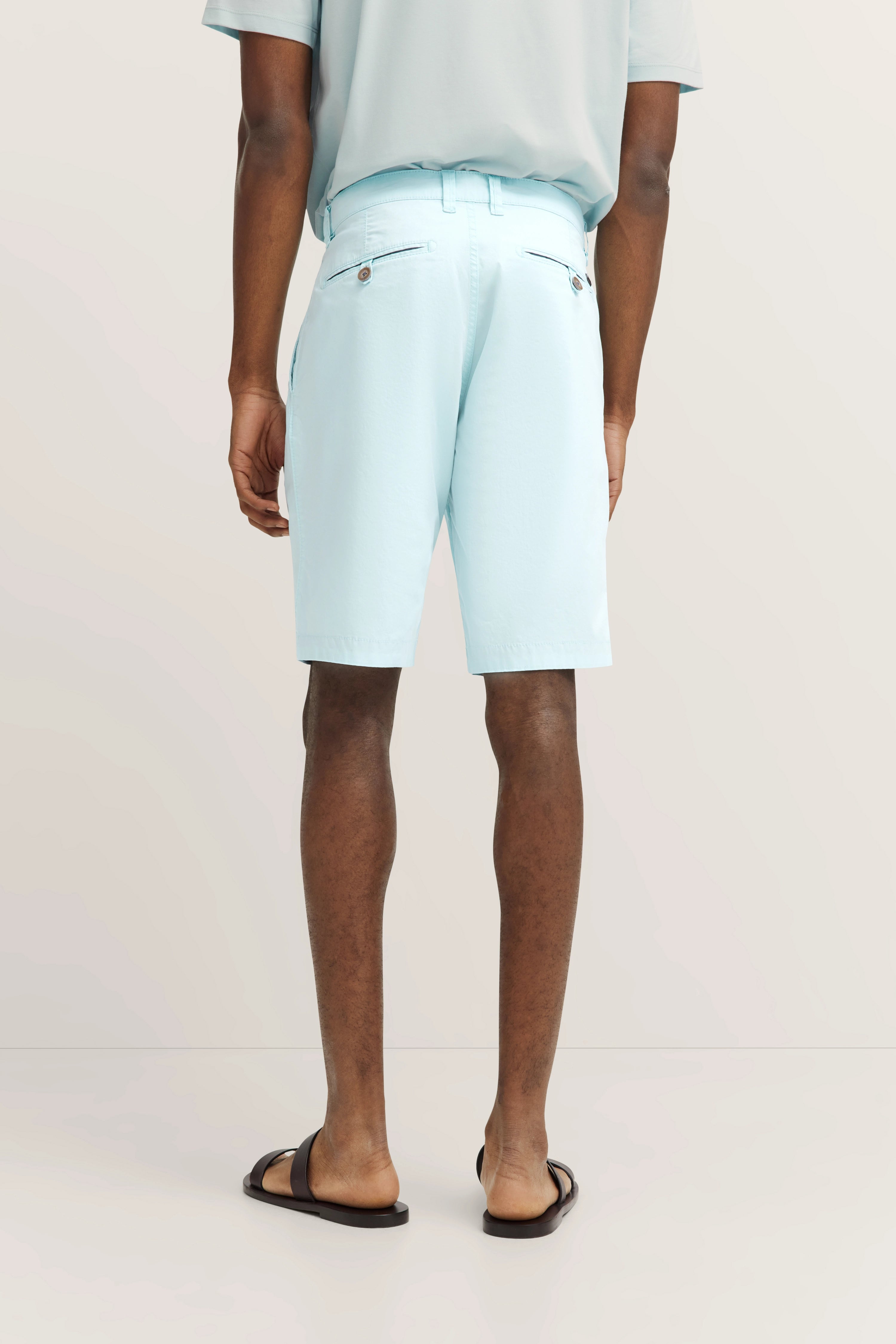 Model trägt hellblaue Shorts und Sandalen, Rückansicht, legerer Look. Perfekt für entspannte Sommermomente.