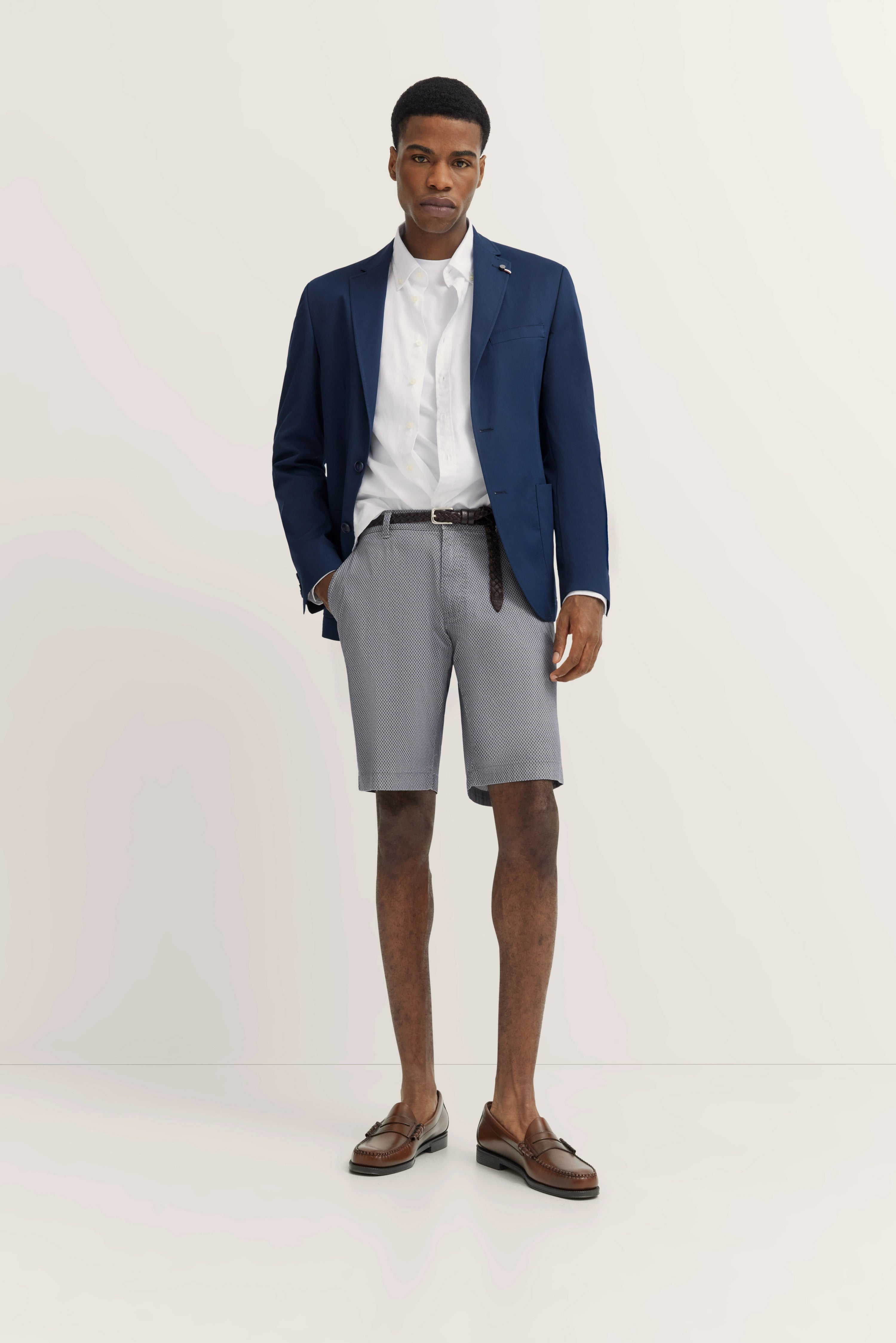 Model in blue blazer, white shirt, and gray shorts by bugatti, embodying timeless elegance and Italian-inspired style.