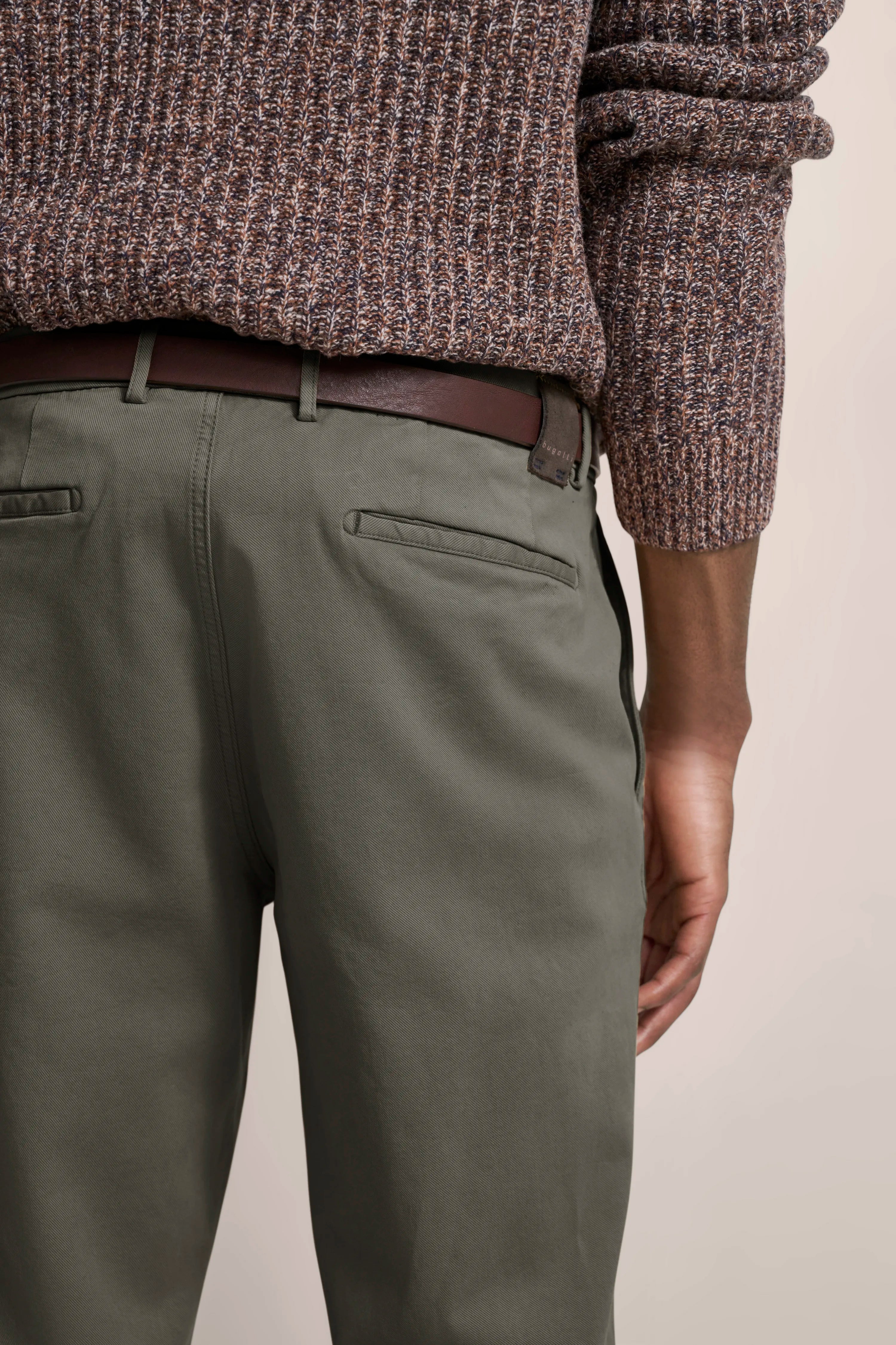 bugatti outfit: Brown knit sweater, green pants, brown belt, casual model image.