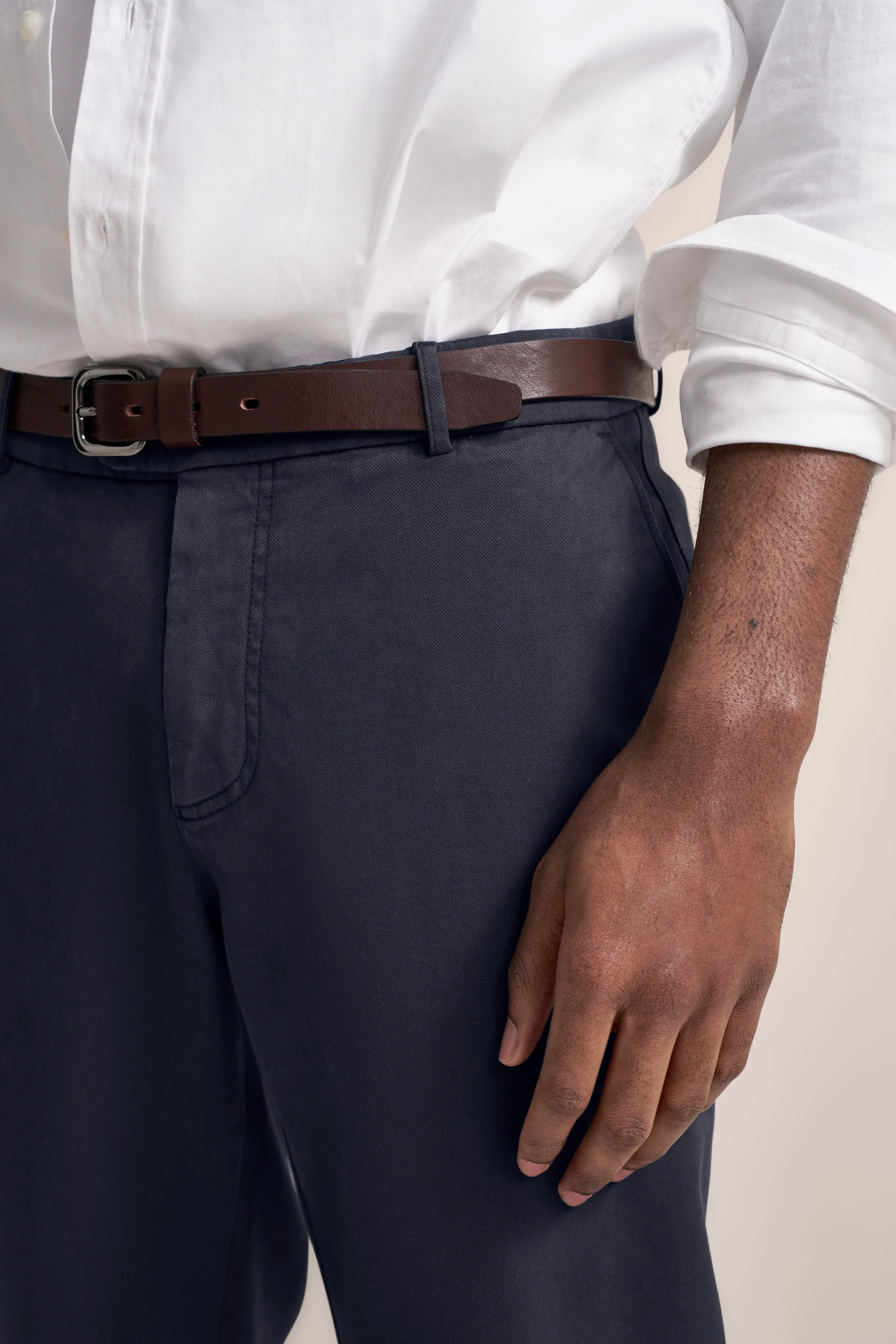 White blouse with dark blue pants and brown belt, casual bust shot, bugatti style.