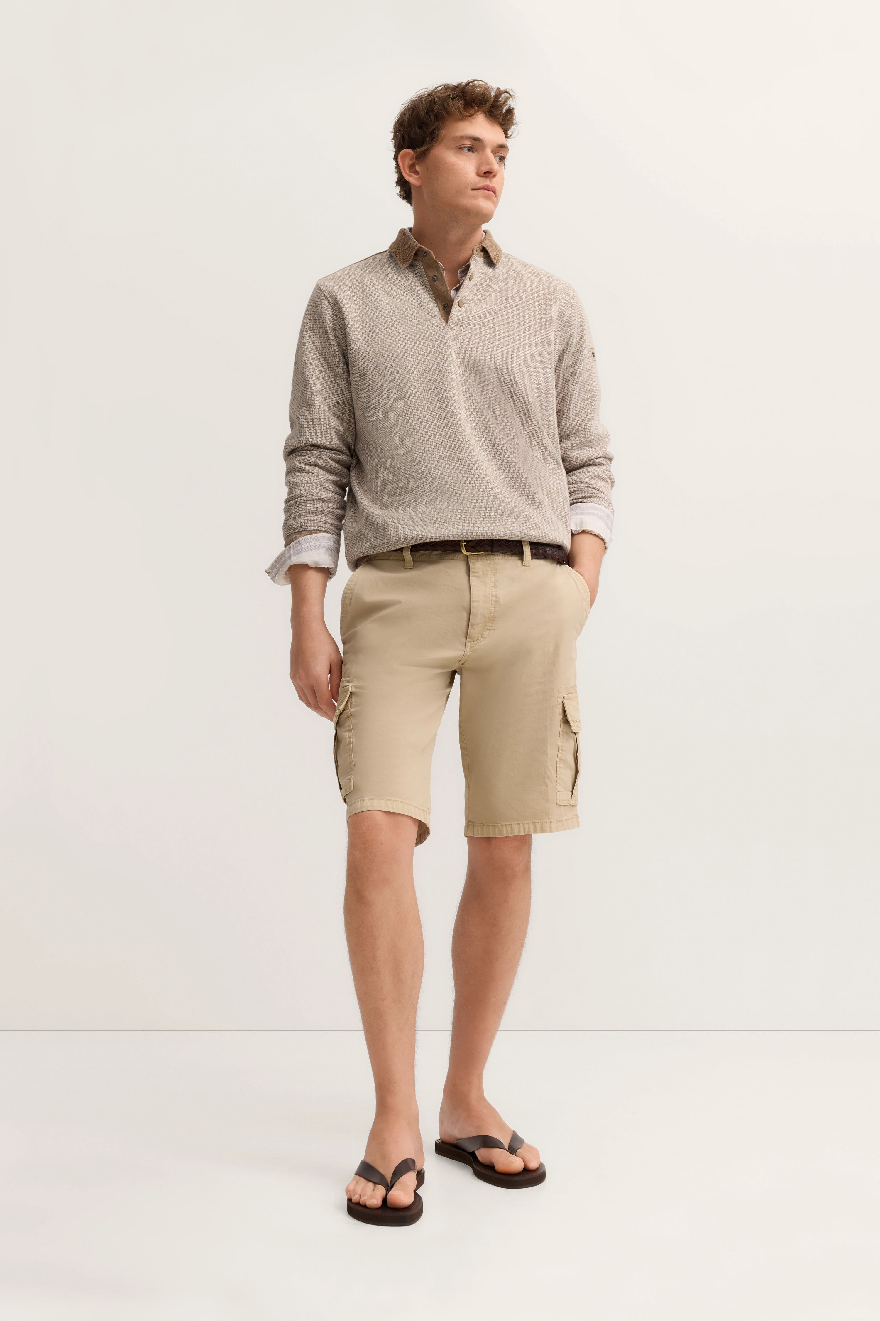 Beiger Pullover und Shorts, Model stehend mit Händen in den Taschen, lässig-eleganter Look von bugatti.