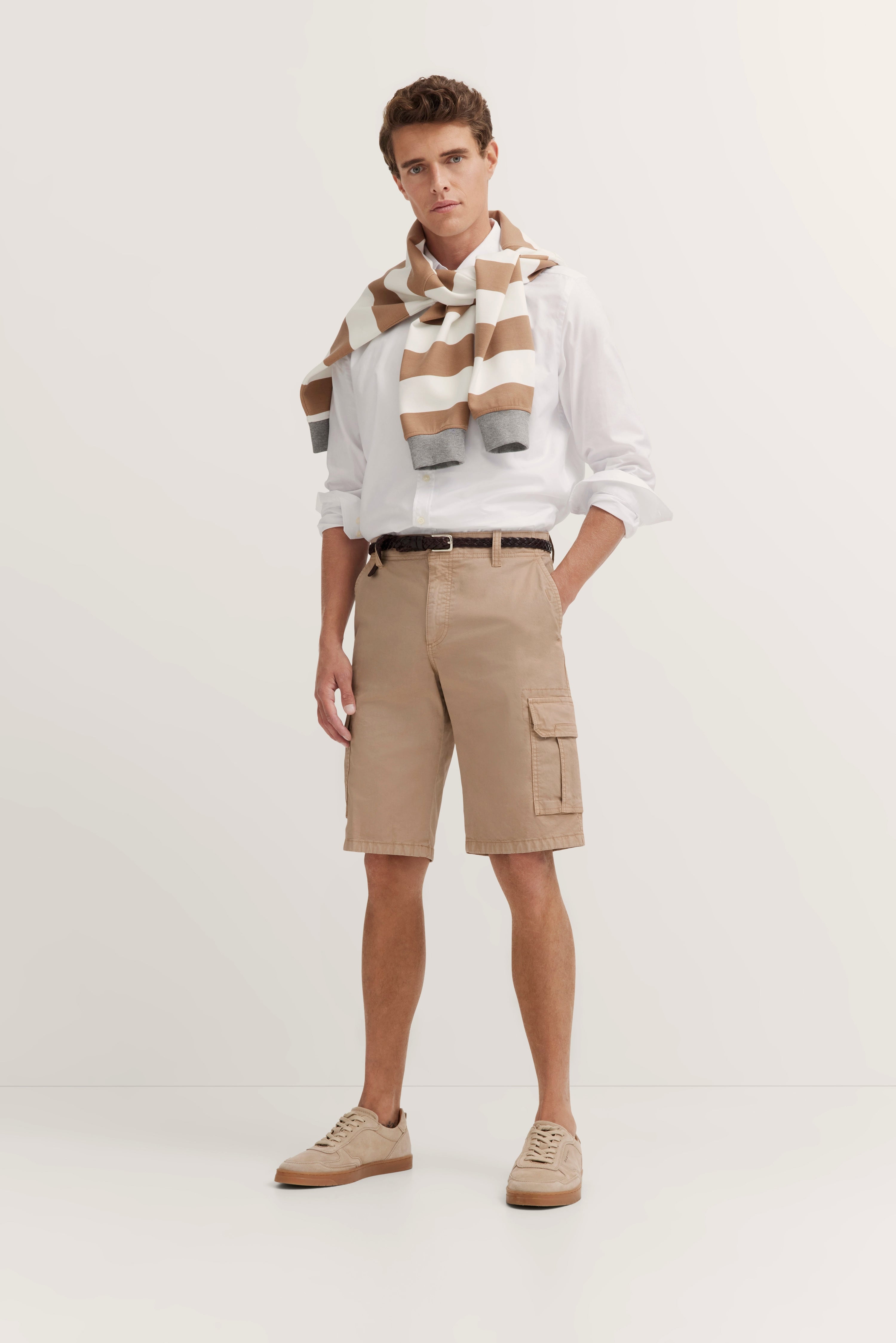 Model in white shirt, beige shorts, striped sweater by bugatti, exuding refined style and timeless elegance.