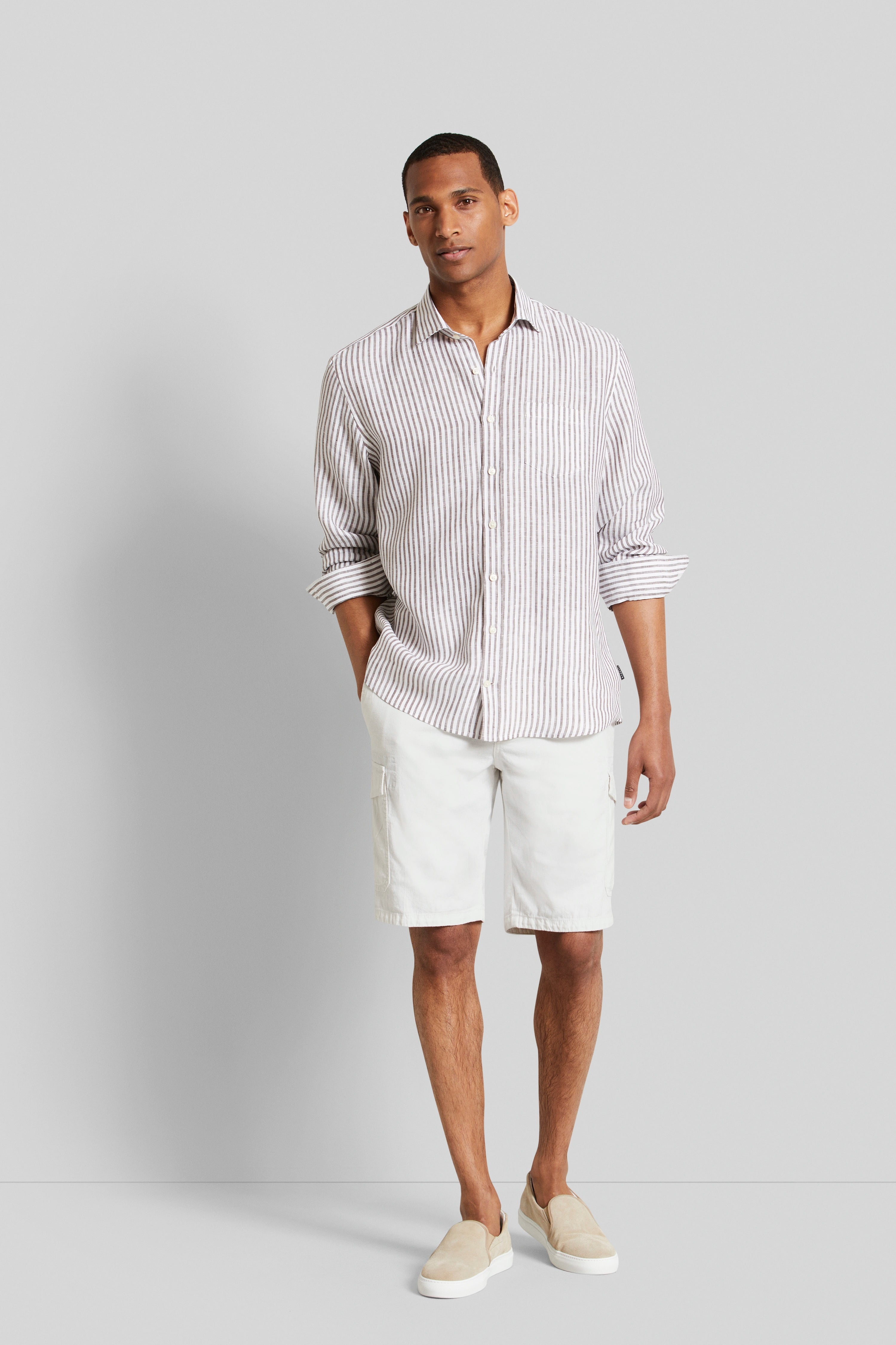 Model in gestreiftem Hemd und weißen Shorts, legeres Posing, bugatti Stil und Eleganz.