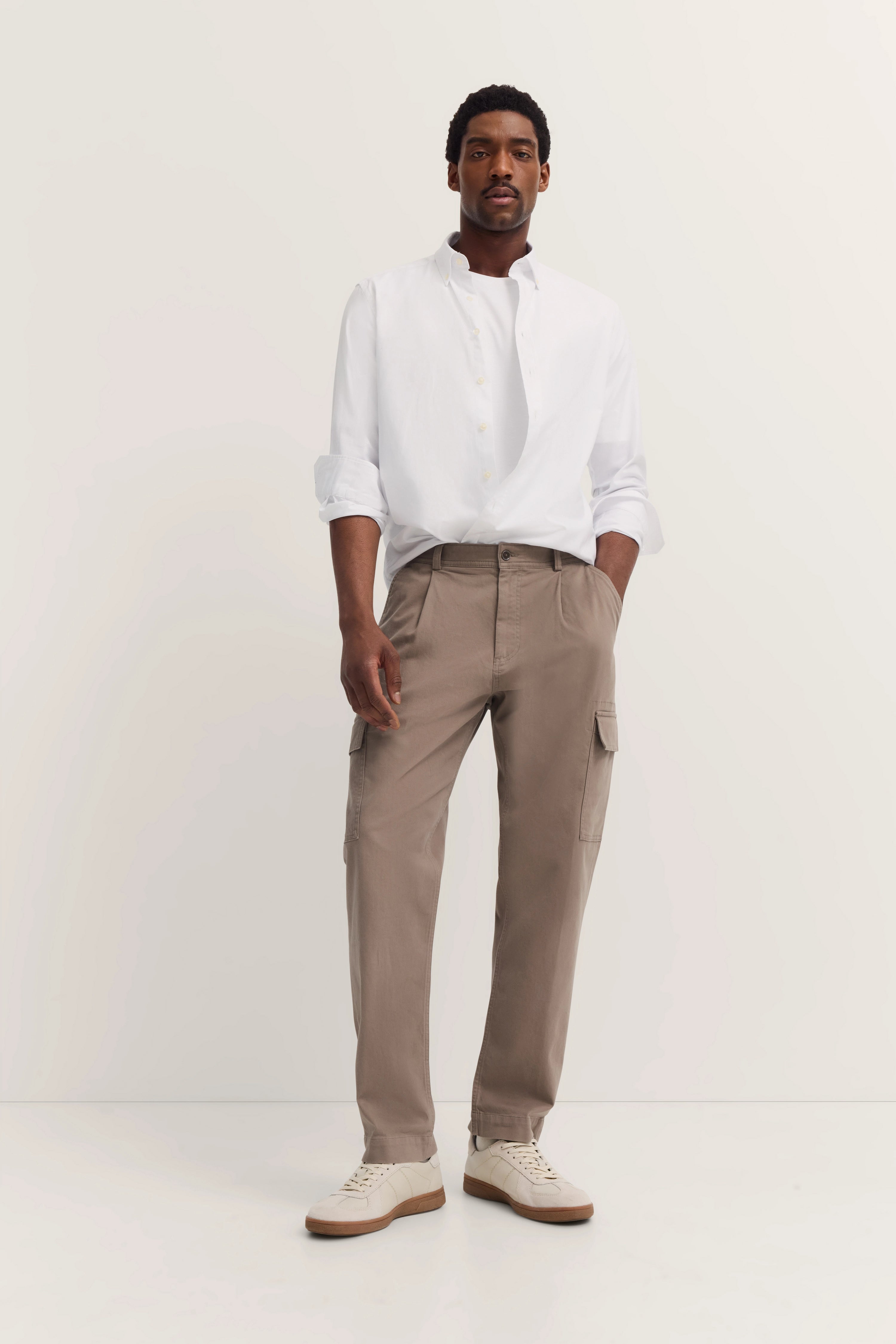Weißes Hemd, beige Cargohose, Model stehend, entspannte Haltung, bugatti Stil.