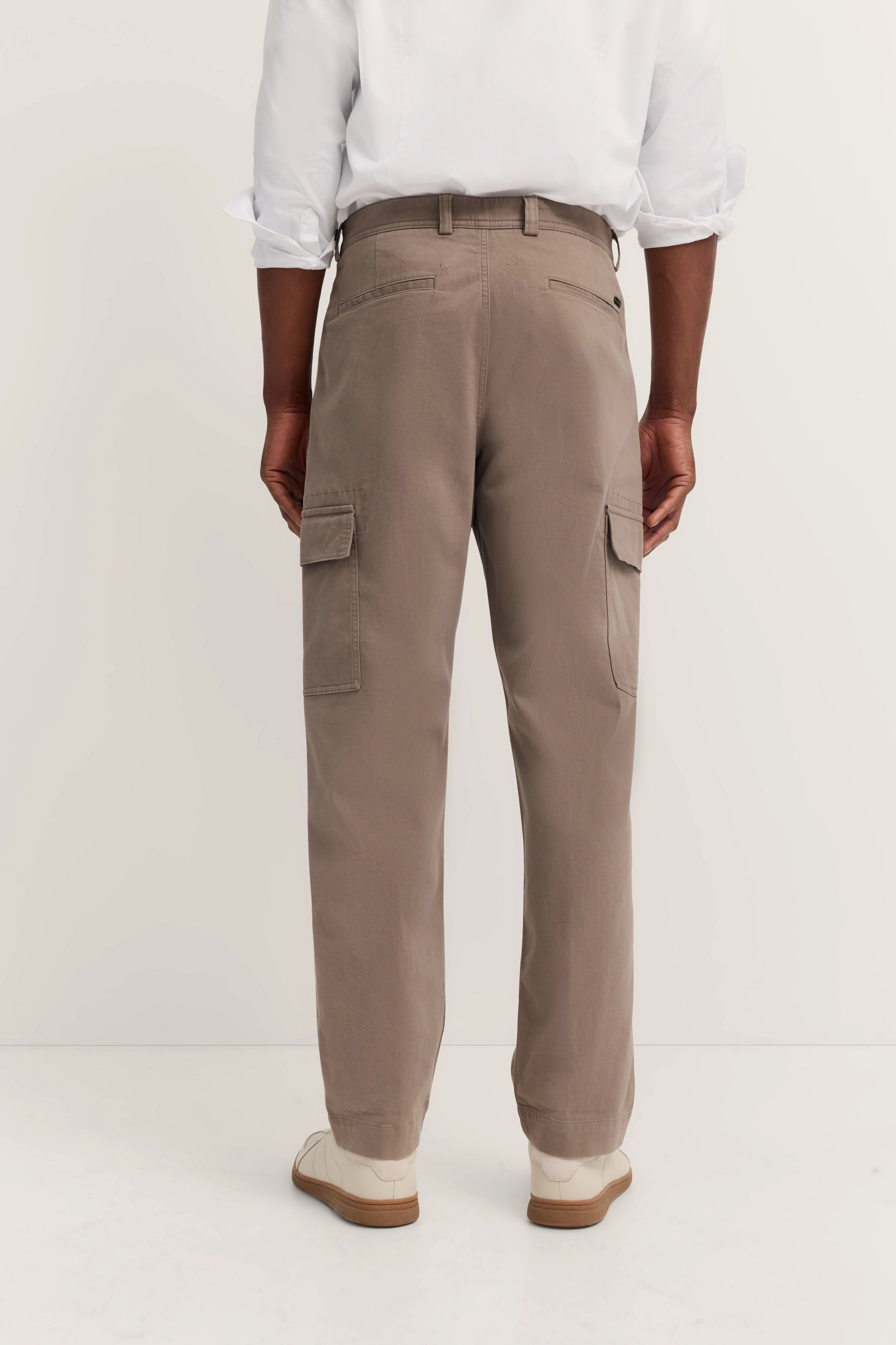 Herrenmodel, beige Cargohose von bugatti, weißes Hemd, legerer Look, Rückansicht.