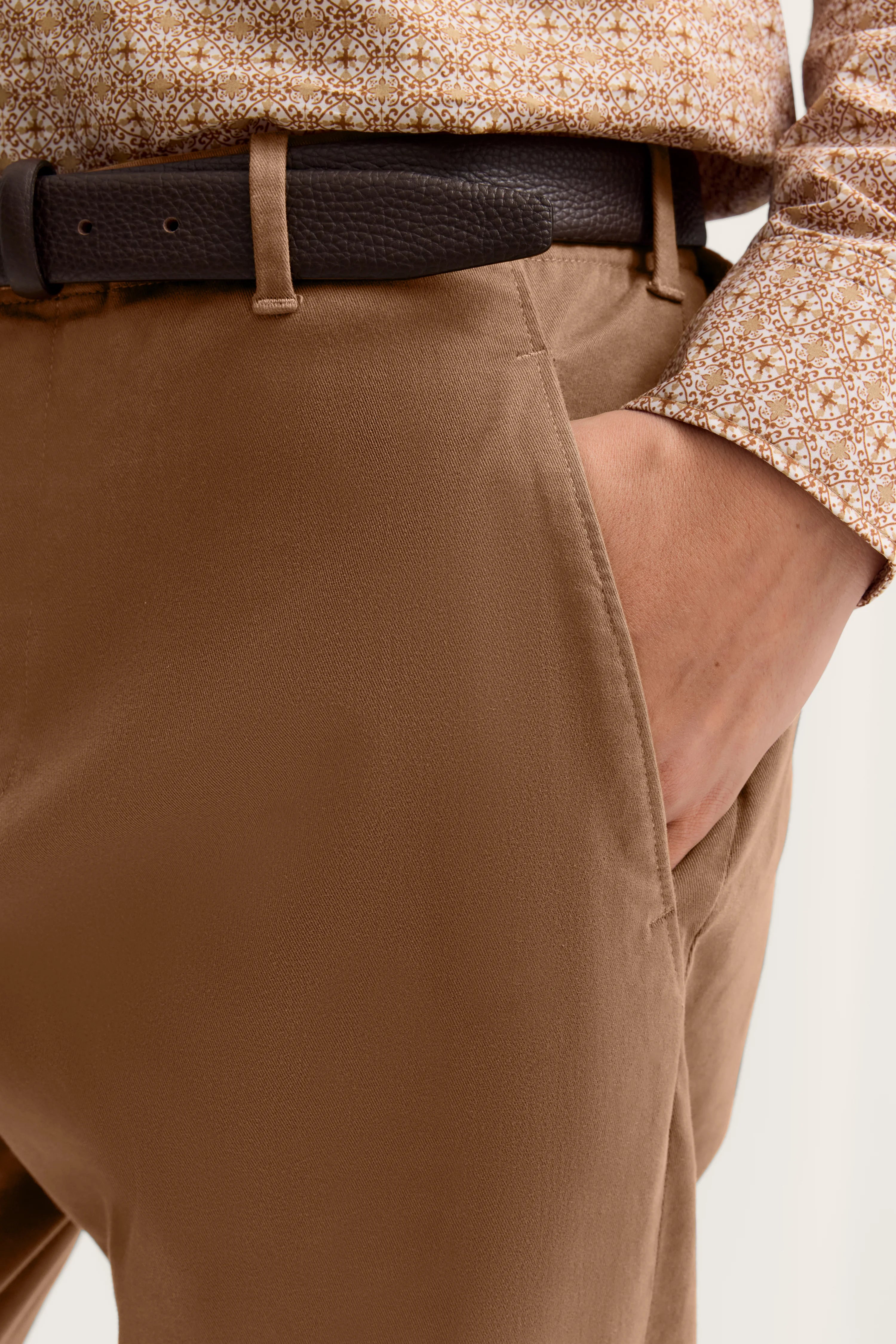 Beige Chinohose mit braunem Gürtel, Detailansicht, gemustertes Hemd, bugatti Stil.