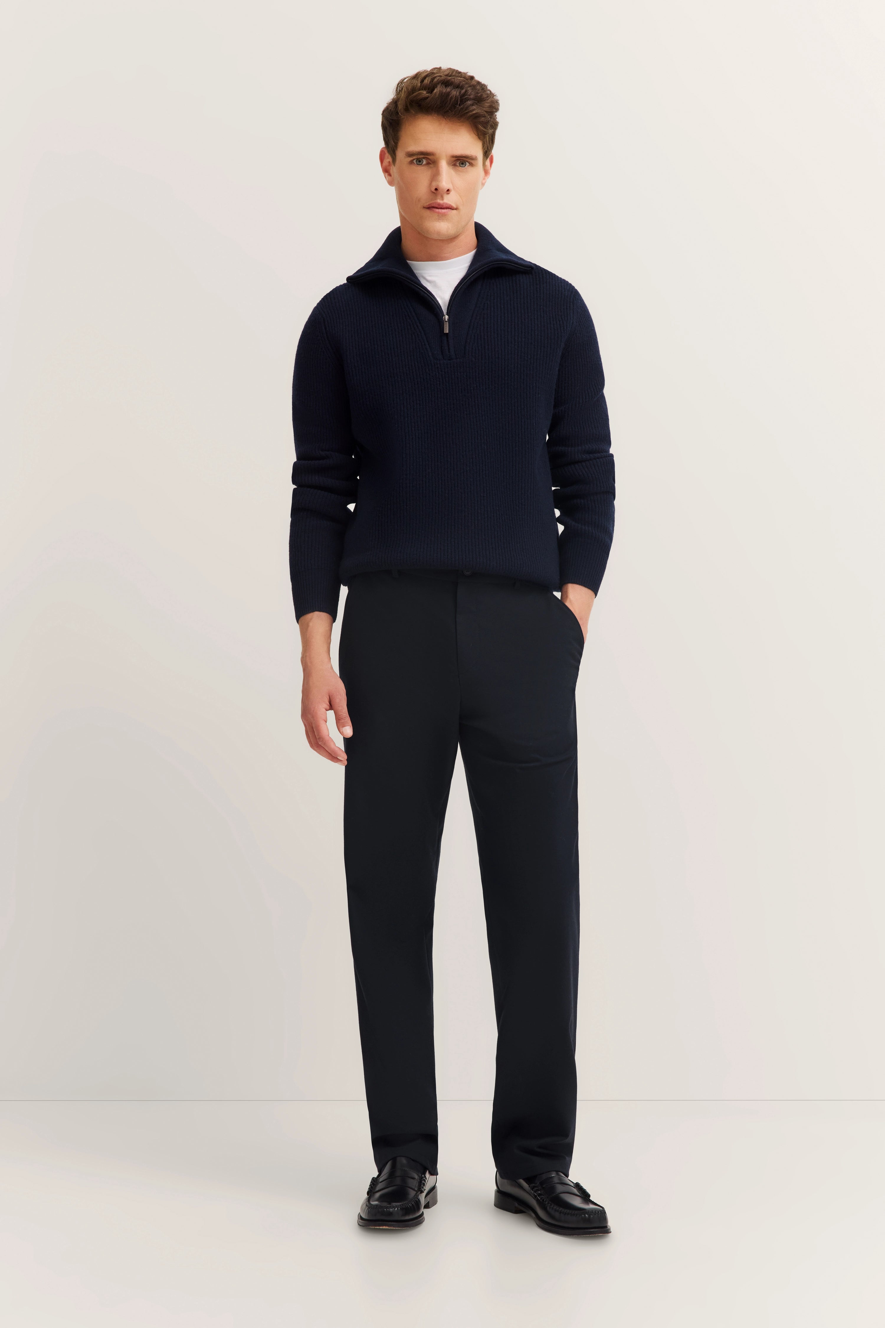 Model in dark bugatti sweater and pants, casual pose, hands in pockets.