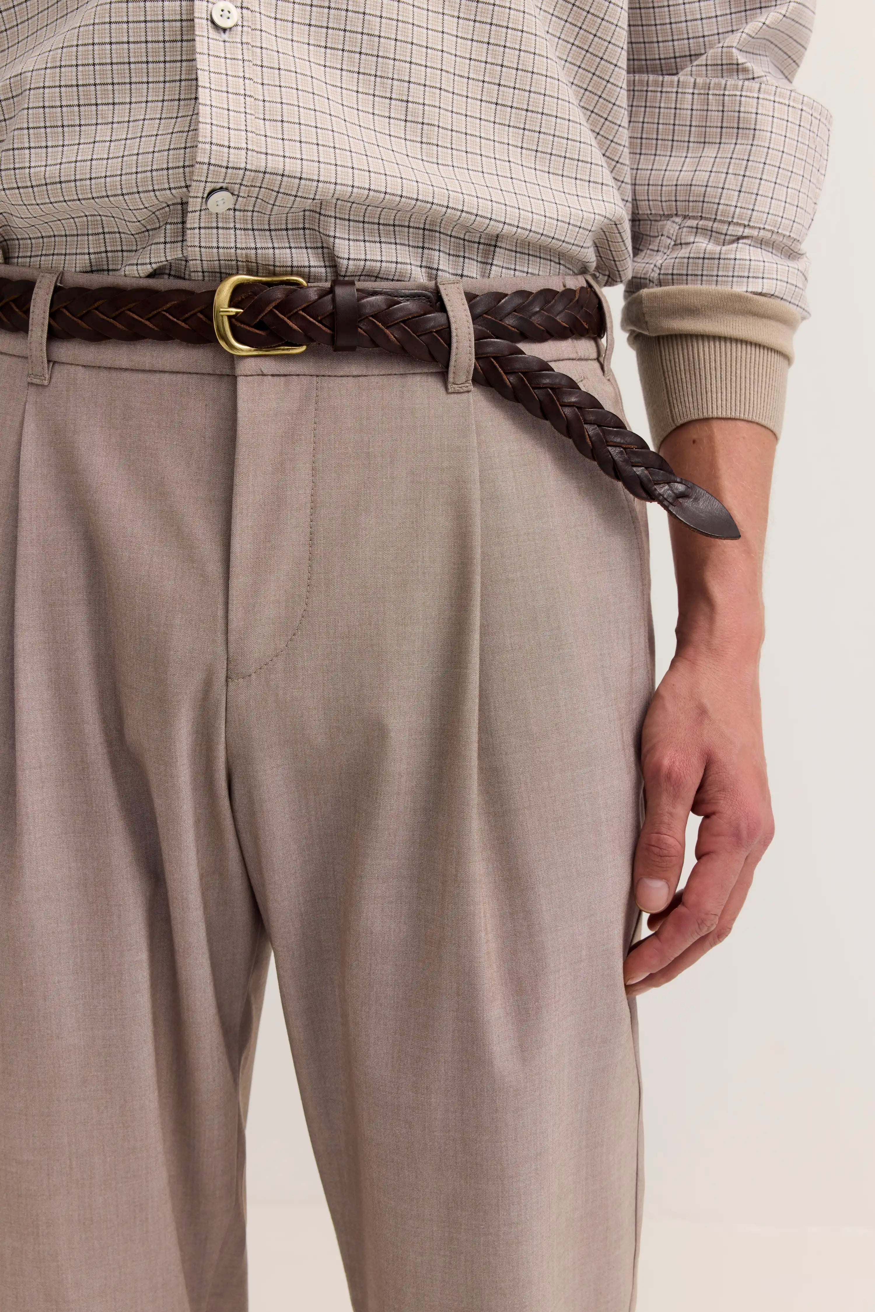 Beigefarbene Hose mit kariertem Hemd, braunem Gürtel, legeres Büstenbild.
