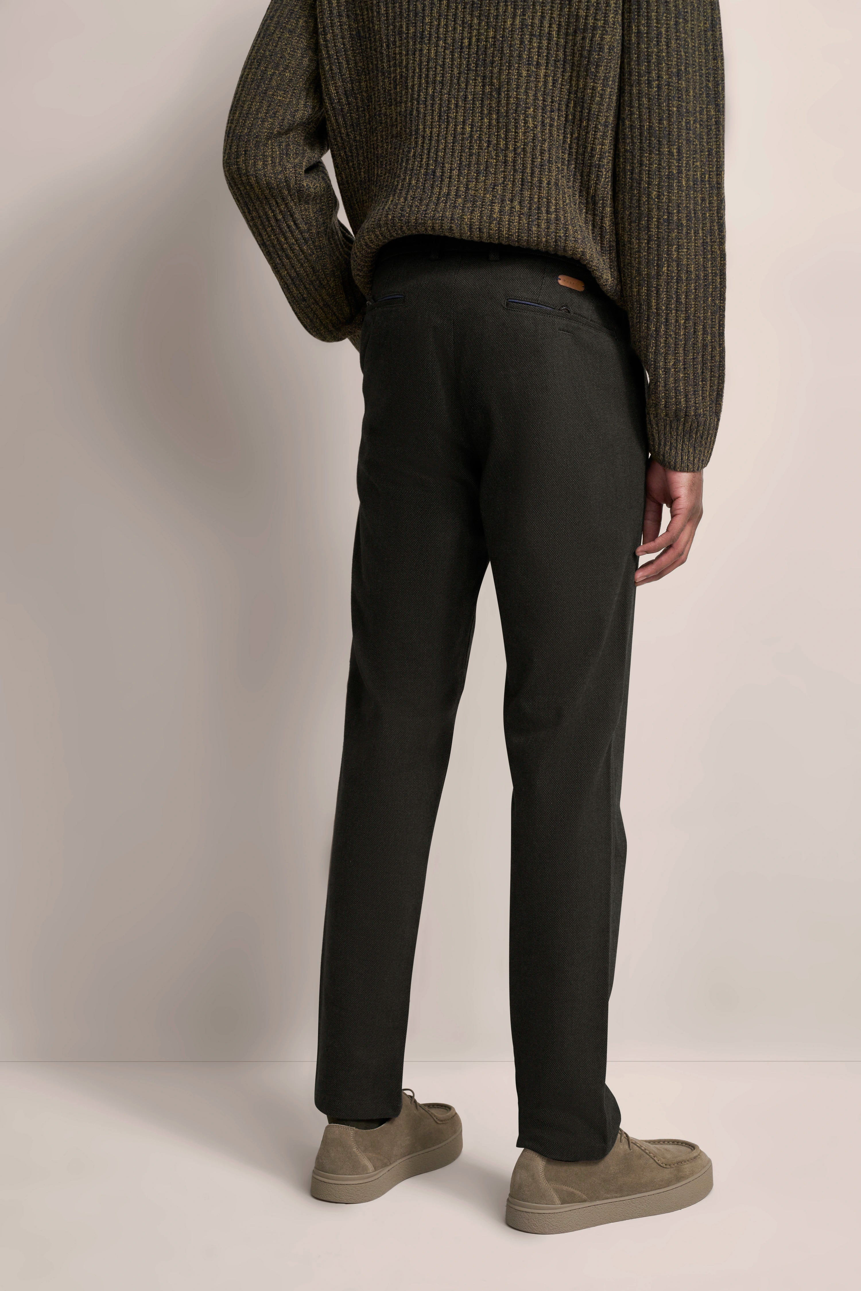 Rückansicht eines Models in olivgrünem Strickpullover und dunkelgrauer Hose von bugatti.