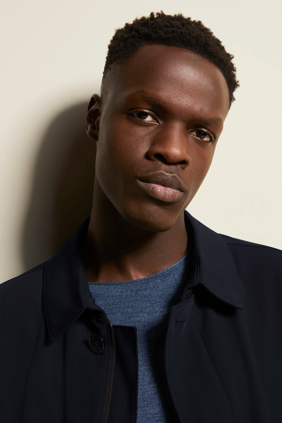 bugatti model in dark blue jacket and blue shirt, relaxed expression.
