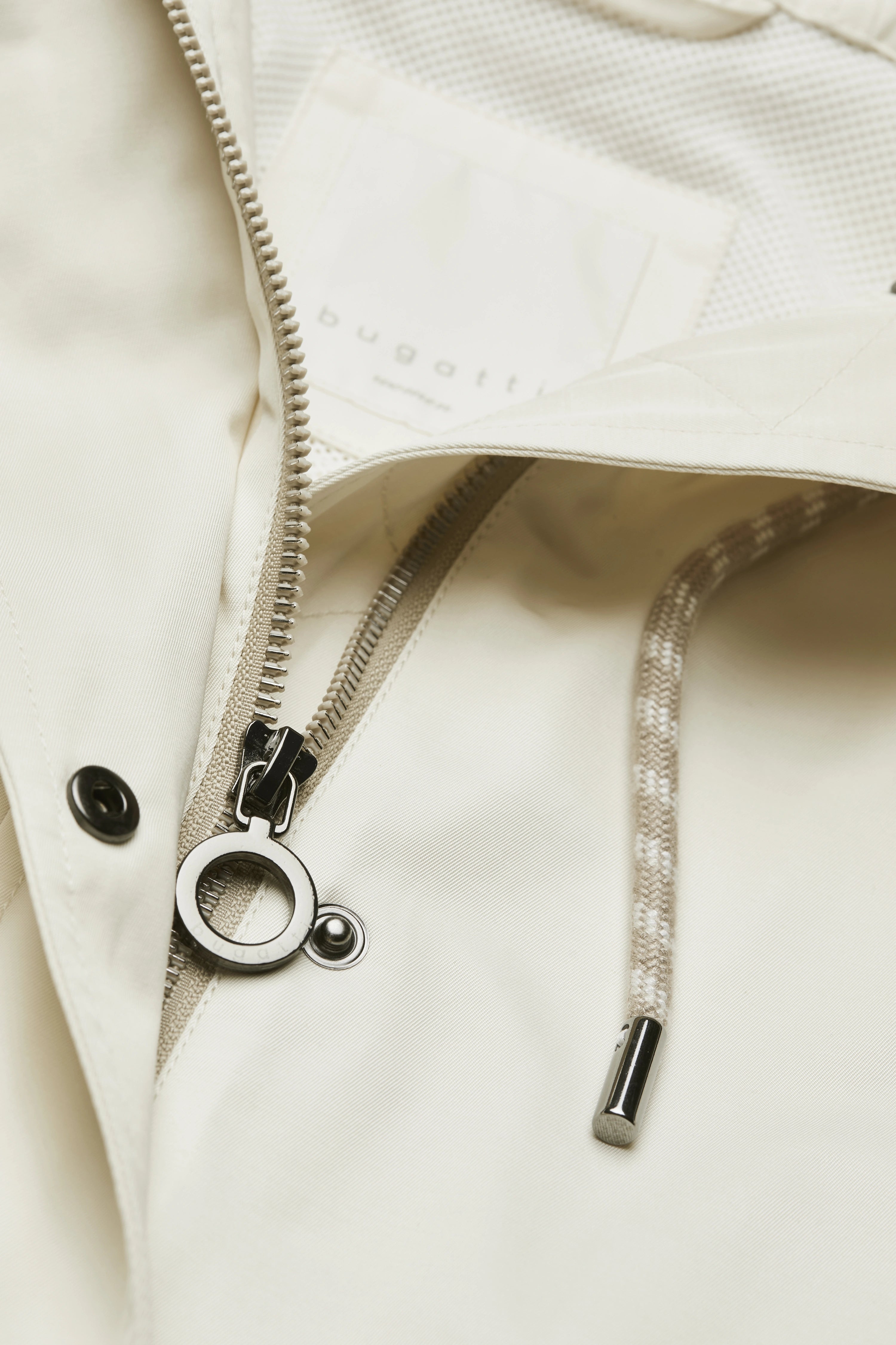 Modelbild mit cremefarbener Kapuzenjacke von bugatti, frontal, dezentes Posing, goldene Ohrringe.