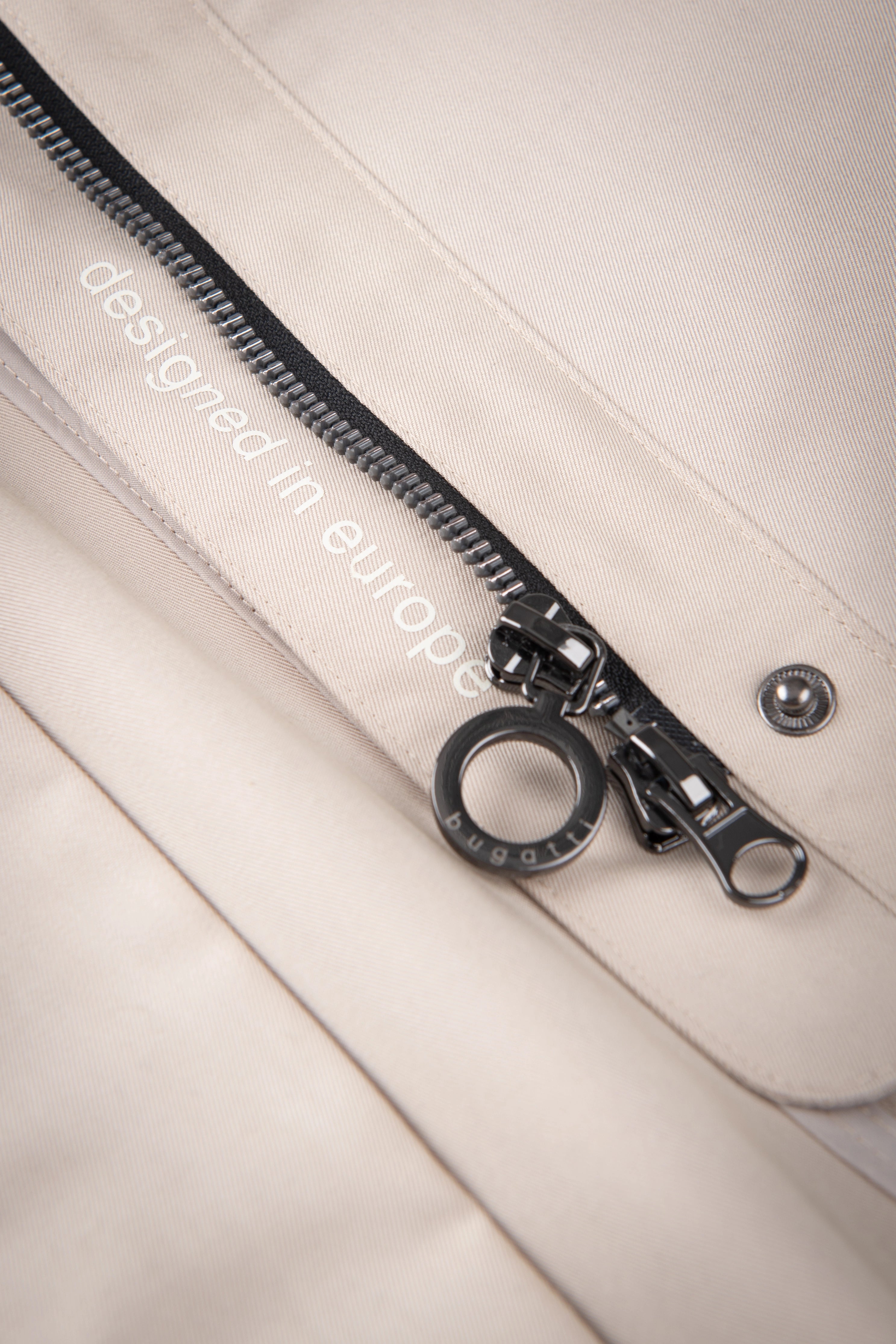 Close-up of beige bugatti outfit with black zipper, detail view.