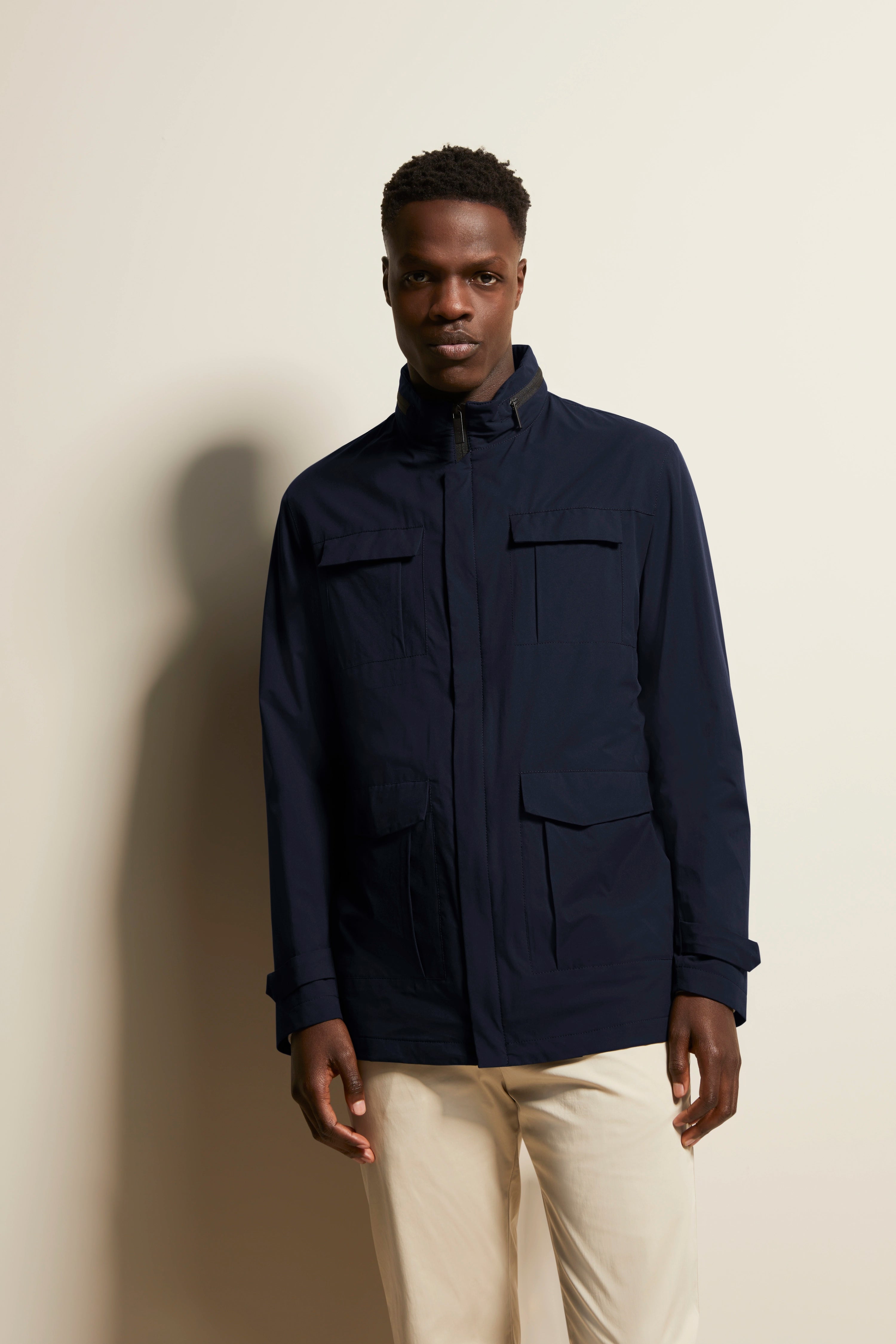 Model trägt bugatti Jacke in Dunkelblau, locker posierend, kombiniert mit hellen Hosen.