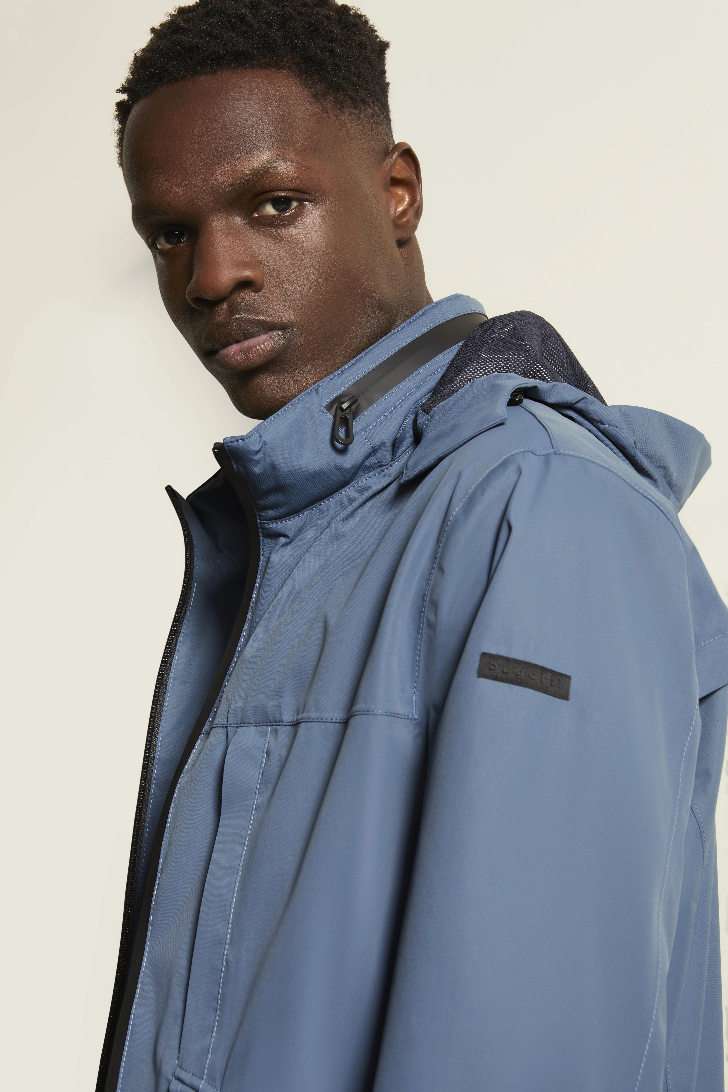 Blaues bugatti Modelbild, Mann trägt sportliche Jacke, entspannter Blick zur Seite.