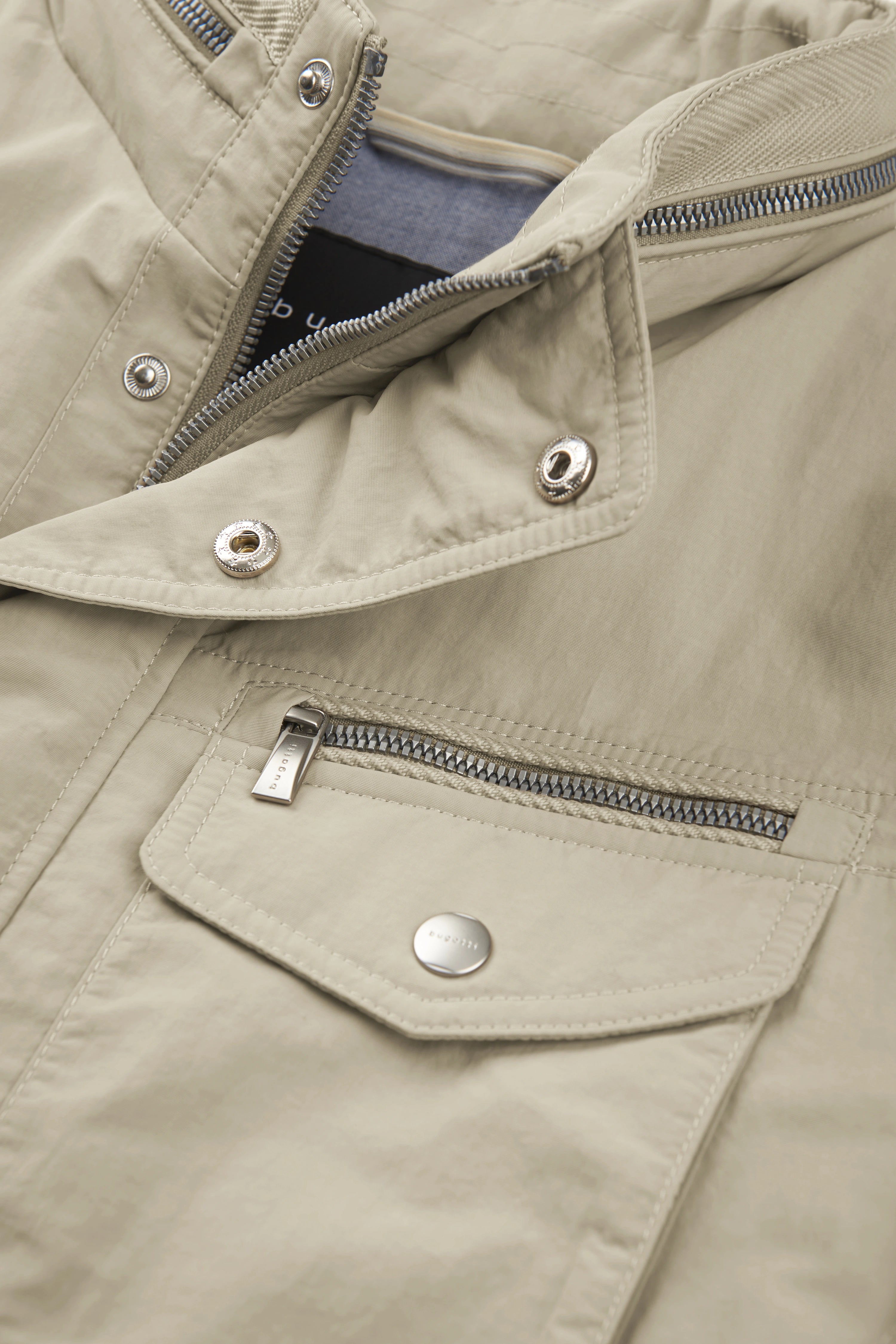 Beige bugatti Jacke mit Reißverschlüssen und Knöpfen, Detailaufnahme.