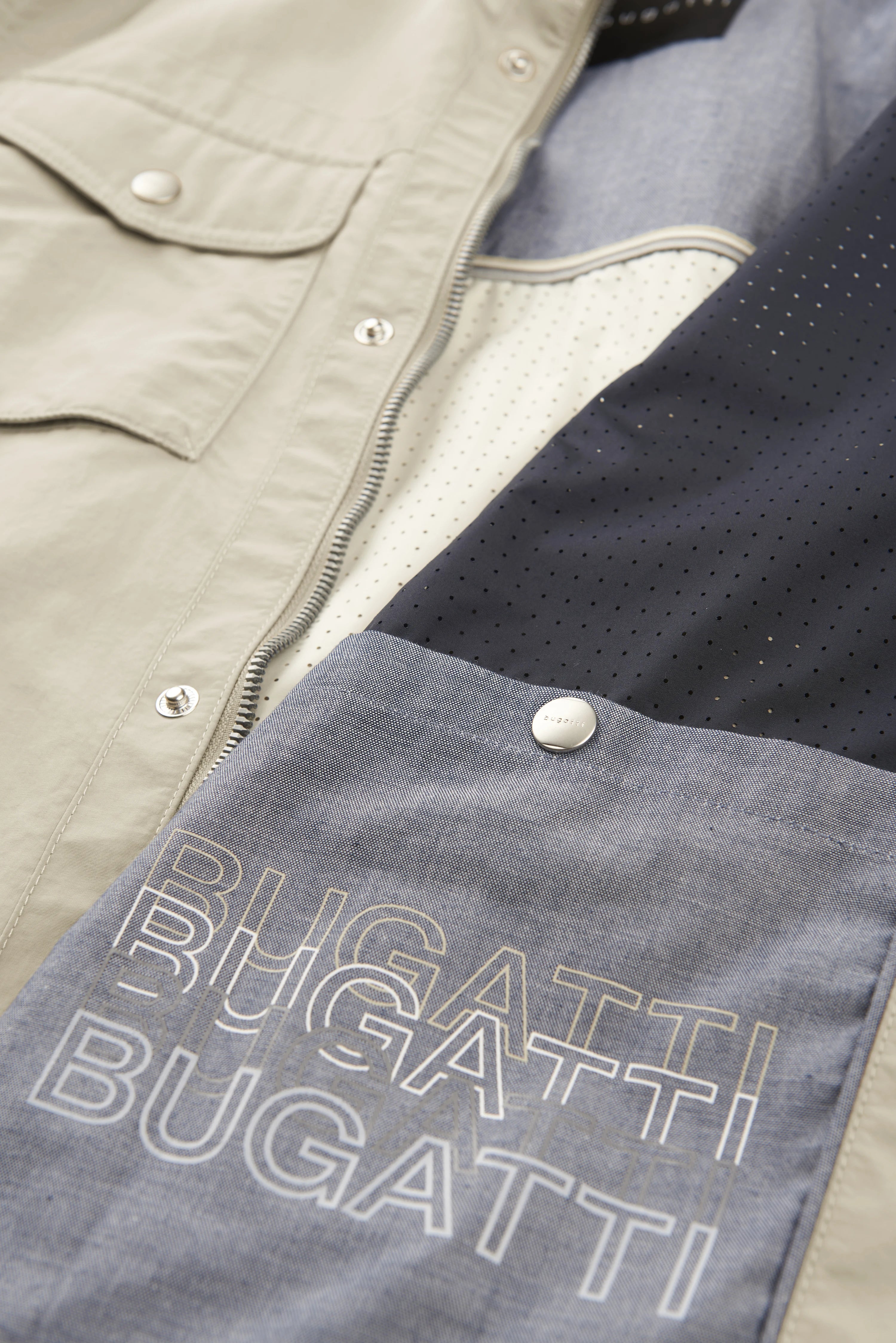 Beiger bugatti Mantel mit blauer Innenseite, perforiertes Design, Detailaufnahme.