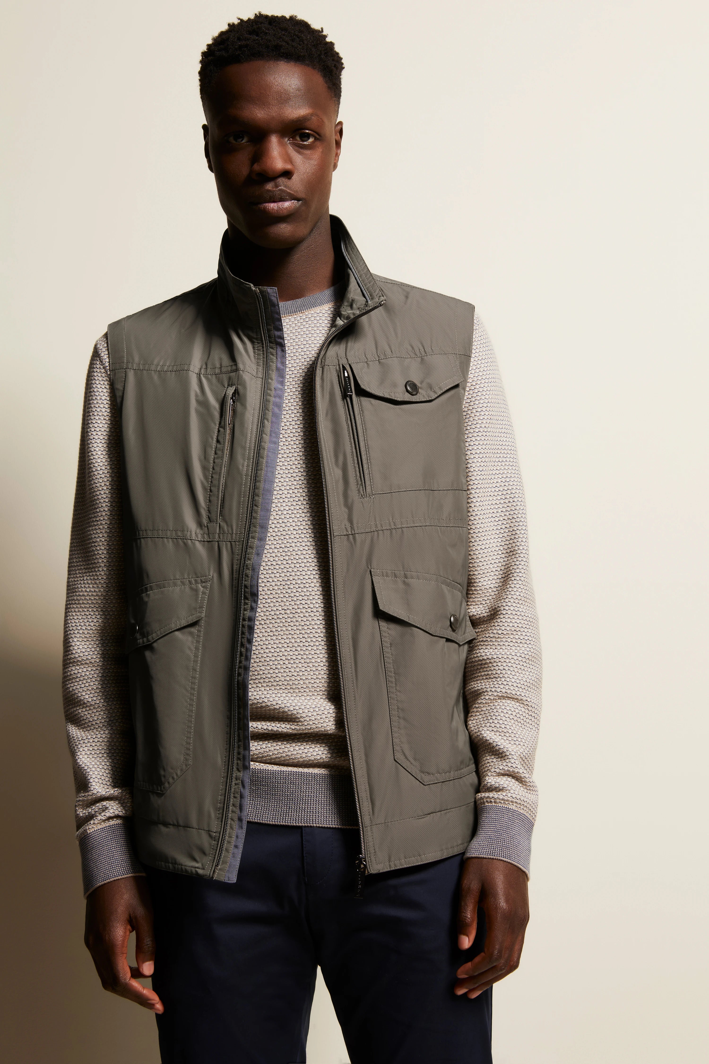 Gray vest and patterned sweater on model, casual pose by bugatti.