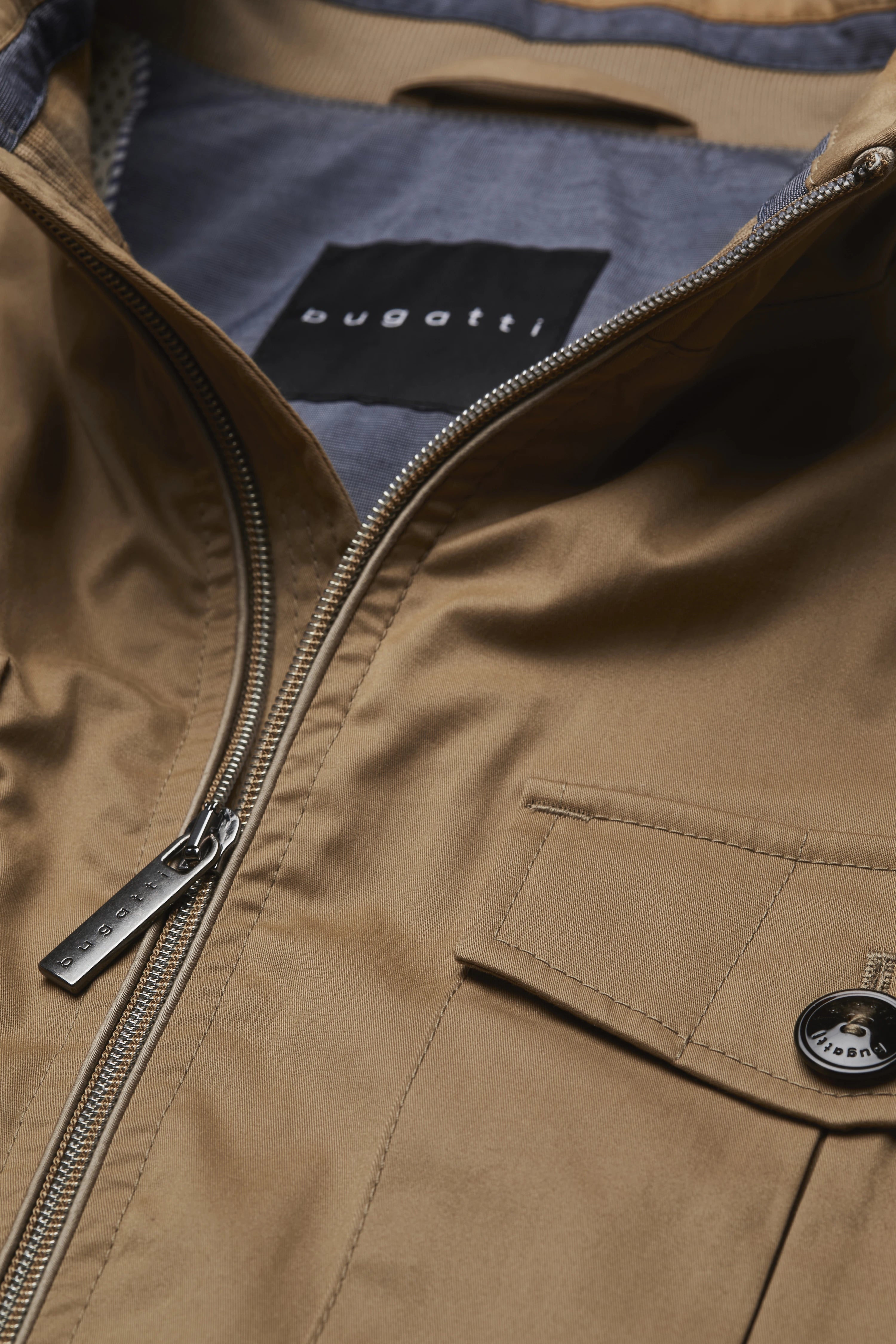 Büste eines Mannes in beigefarbener bugatti-Jacke mit blauem Hemdkragen.