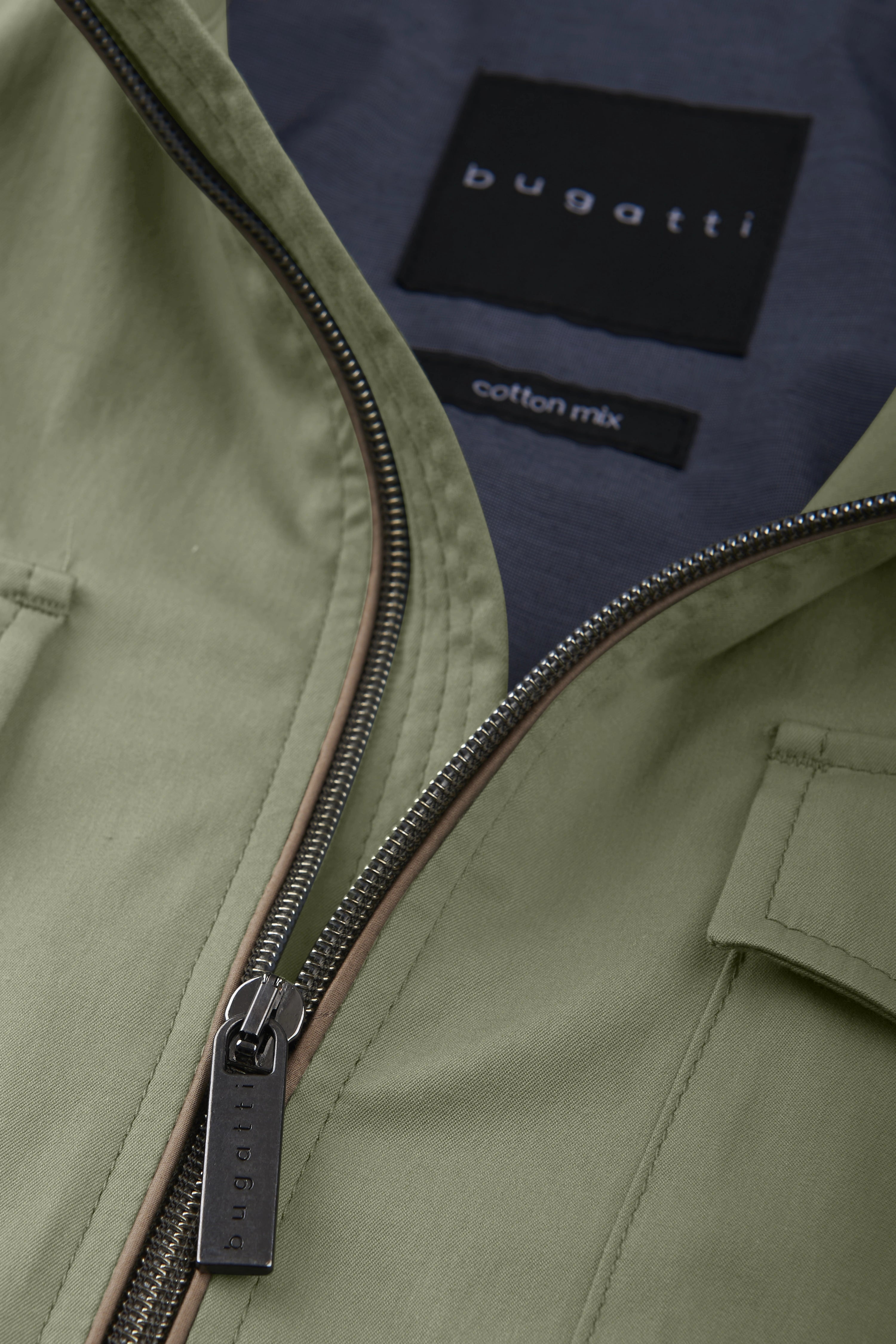 Grüne bugatti Jacke, Detailansicht mit Reißverschluss und Label, aus Baumwollmix.