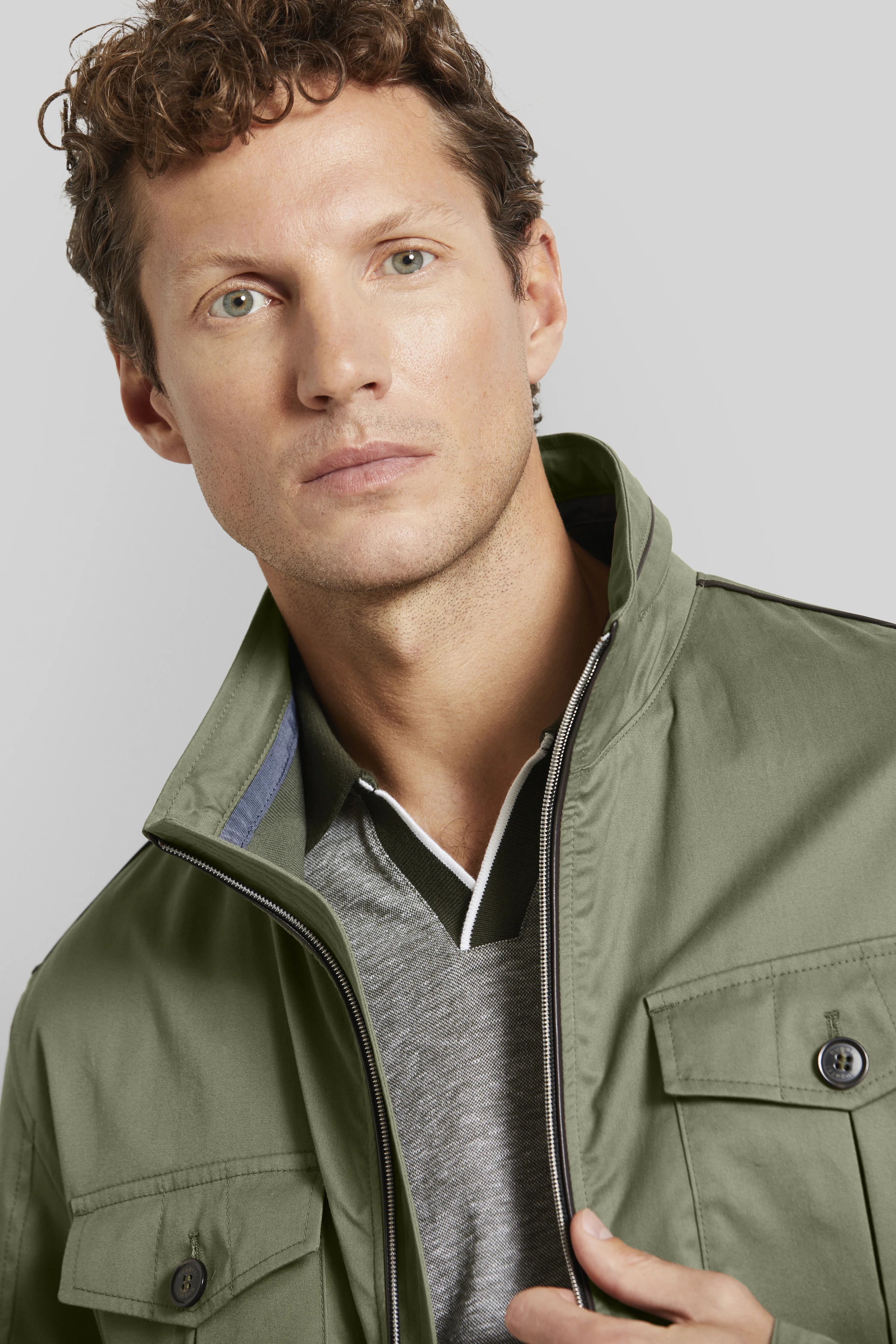 Grünes bugatti-Jackett, graues Polo, Modelbild, entspannter Blick.